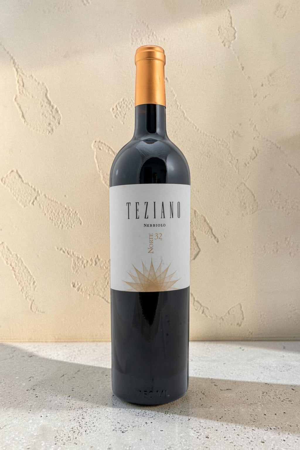 Botella de vino tinto Wellnex Teziano Nebiolo con etiqueta elegante y cápsula dorada sobre fondo de piedra clara