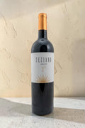 Botella de vino tinto Wellnex Teziano Nebiolo con etiqueta elegante y cápsula dorada sobre fondo de piedra clara