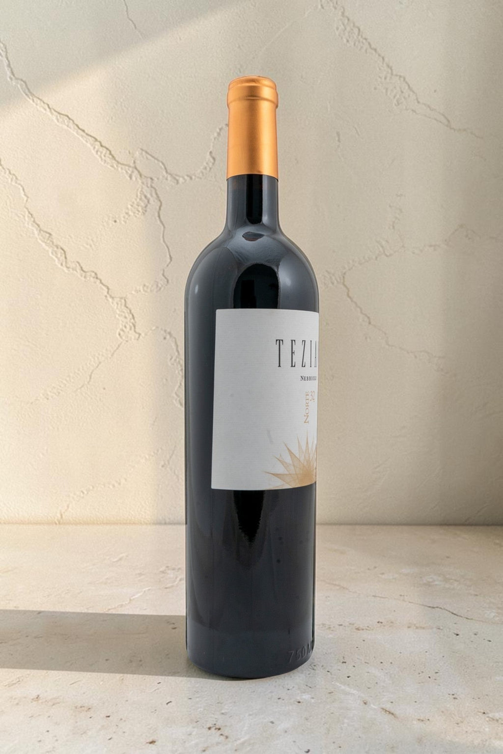Botella de vino tinto Wellnex Teziano Nebiolo con etiqueta elegante y cápsula dorada sobre superficie de piedra