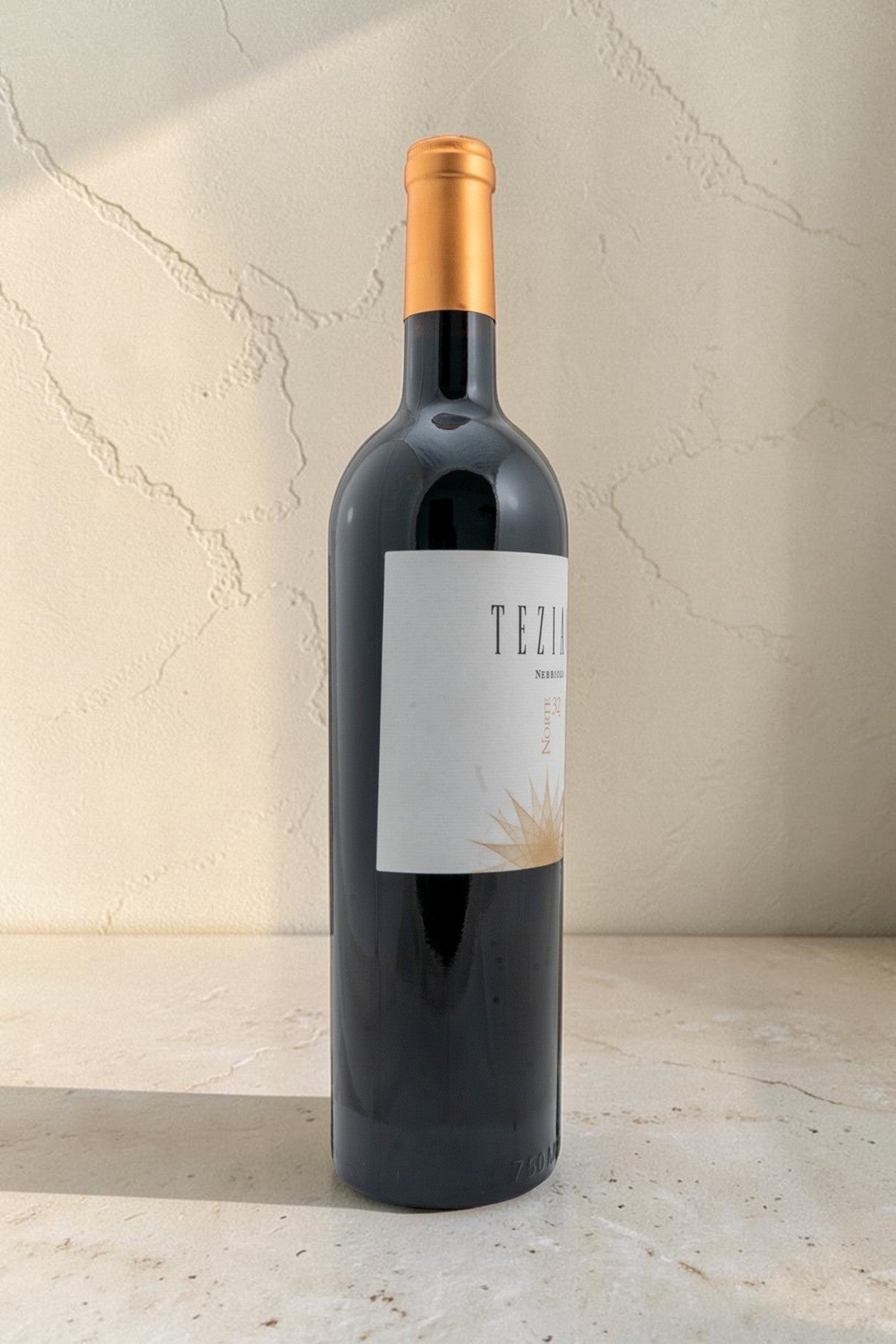 Botella de vino tinto Wellnex Teziano Nebiolo con etiqueta elegante y cápsula dorada sobre superficie de piedra