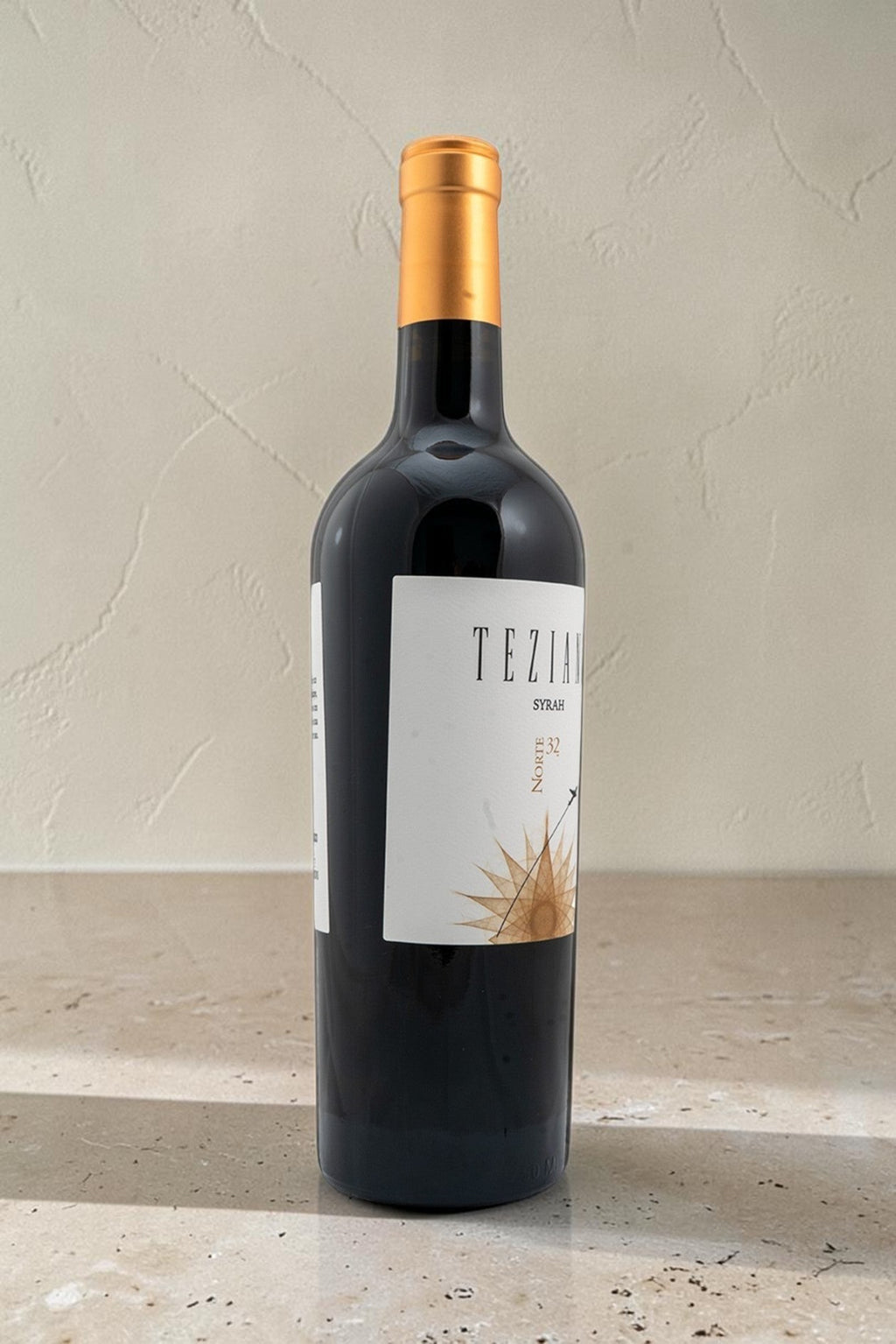 Botella de vino tinto Wellnex Teziano Syrah con etiqueta elegante y cápsula dorada sobre superficie de piedra