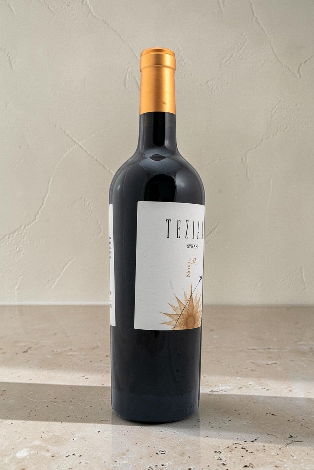 Botella de vino tinto Wellnex Teziano Syrah con etiqueta elegante y cápsula dorada sobre superficie de piedra
