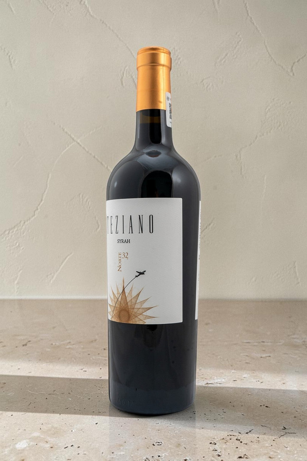 Botella de vino tinto Wellnex Teziano Syrah con etiqueta elegante y cápsula dorada sobre superficie de piedra