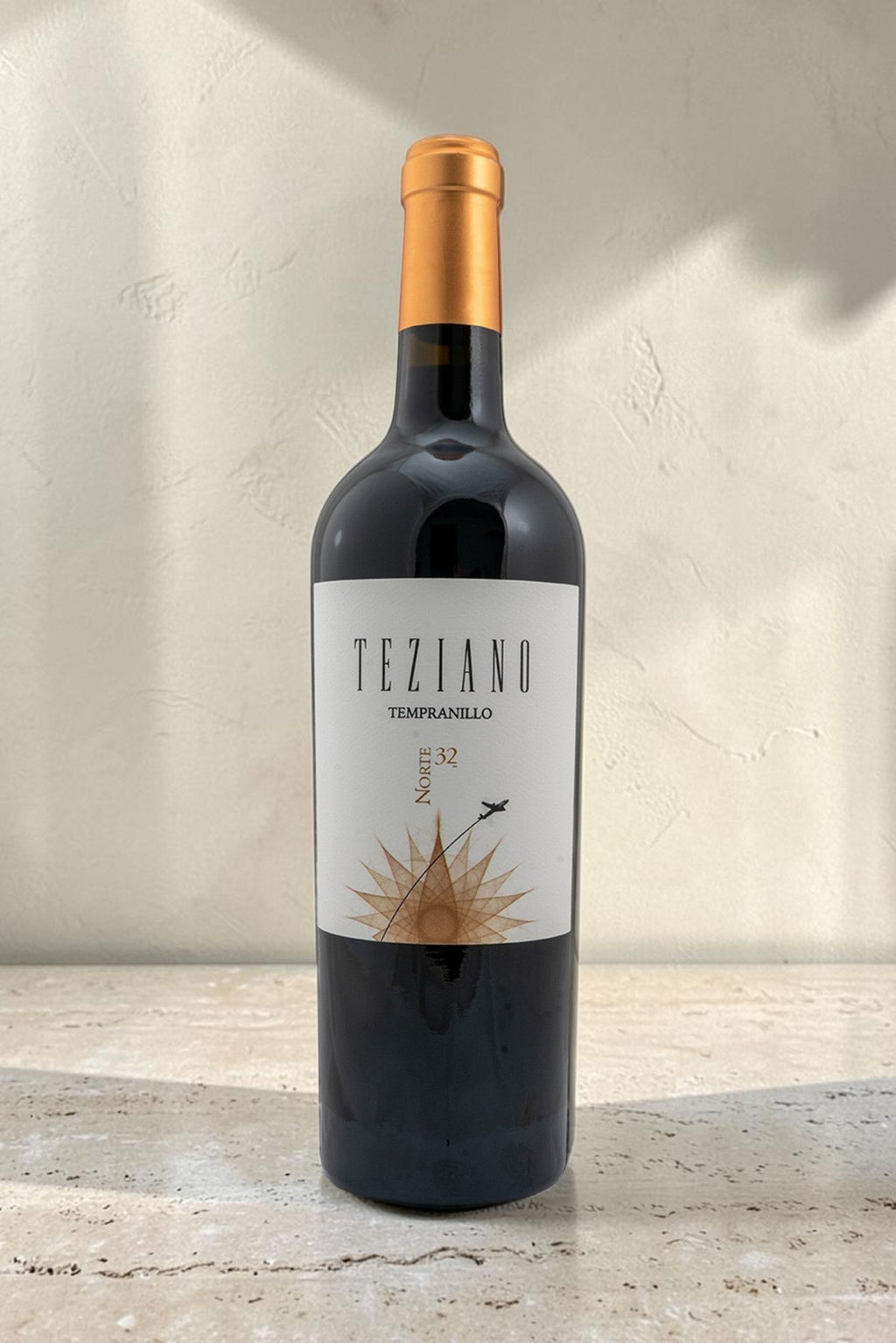 Botella de vino tinto Wellnex Teziano Tempranillo con etiqueta elegante y tapón dorado sobre superficie de piedra