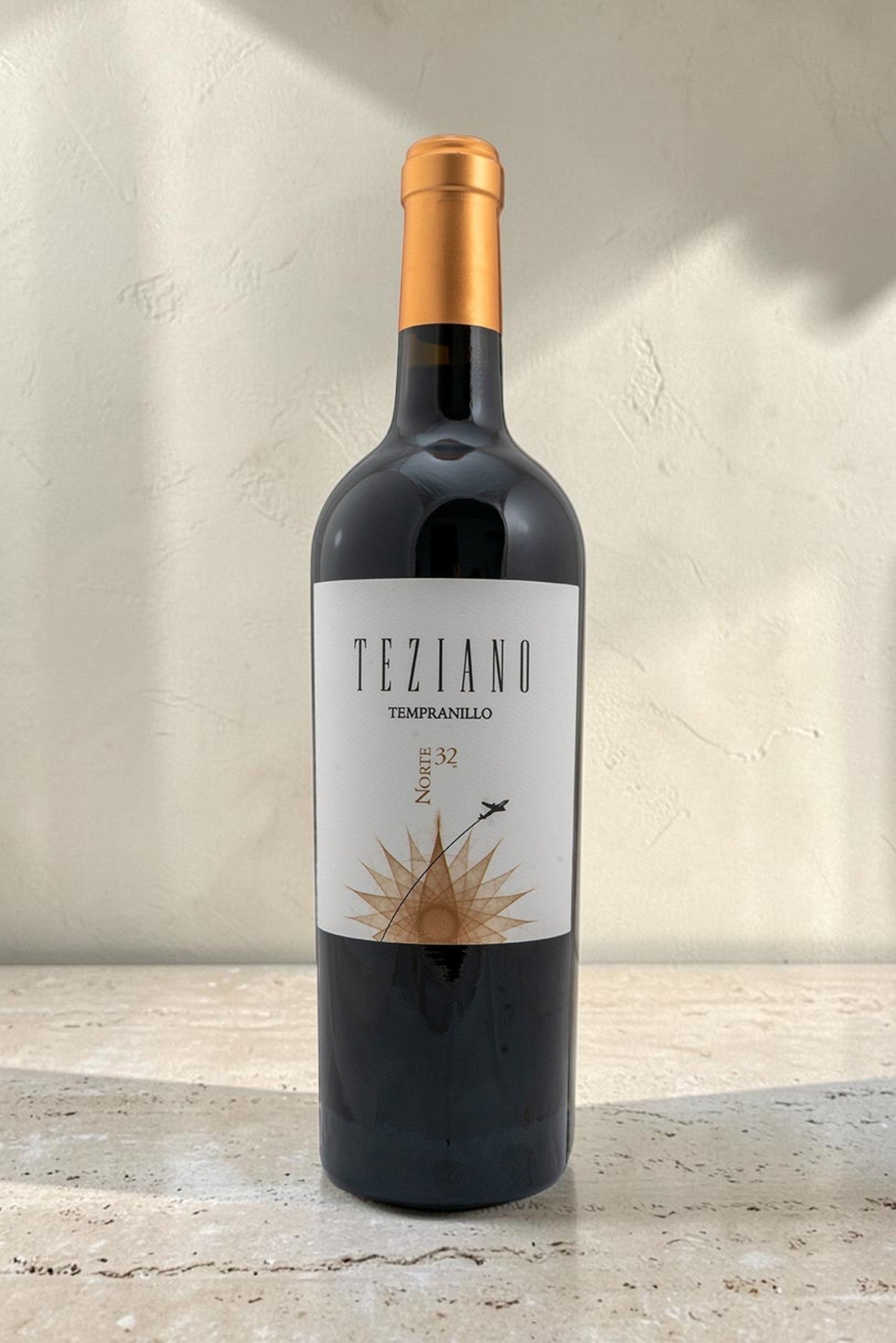 Botella de vino tinto Wellnex Teziano Tempranillo con etiqueta elegante y tapón dorado sobre superficie de piedra