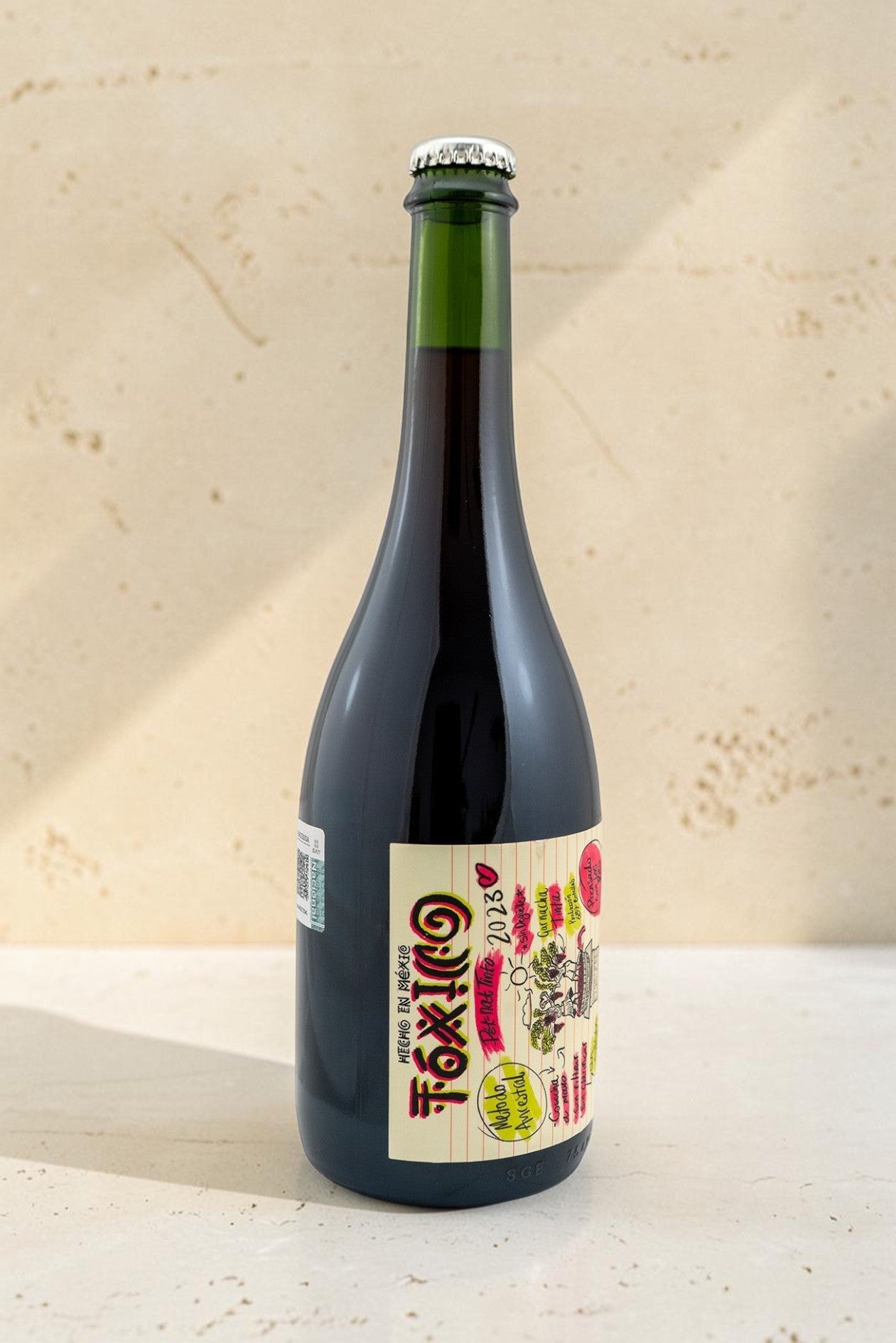 Botella de vino tinto Wellnex Toxico con etiqueta ilustrada colorida y tapa corona sobre superficie clara