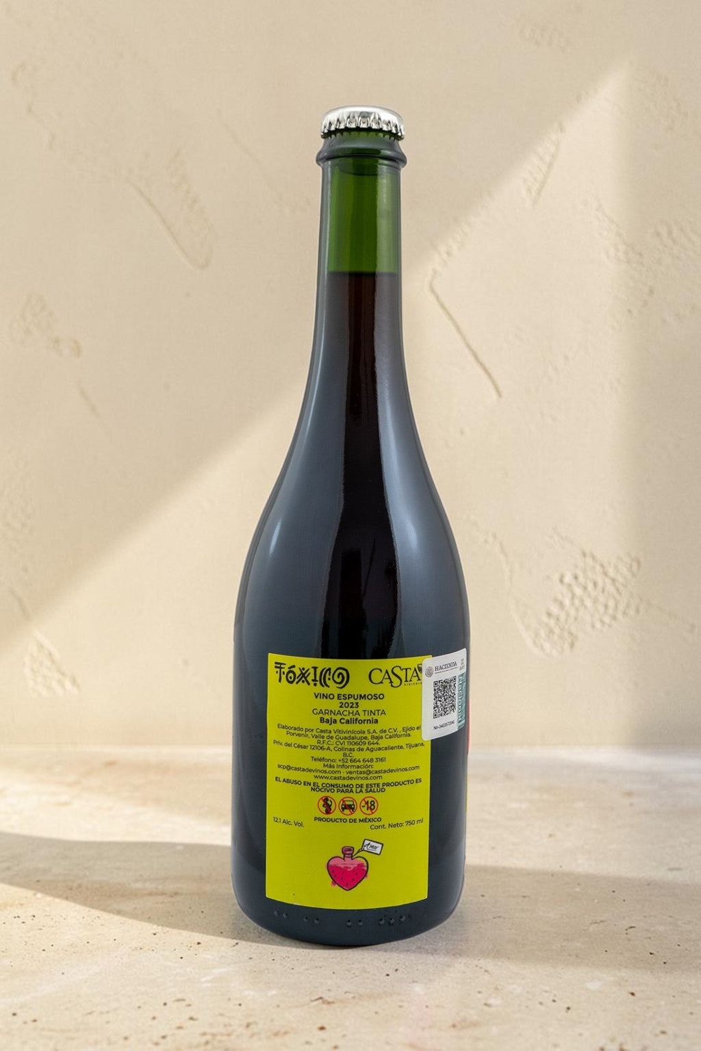 Botella de vino tinto espumoso Toxico de Wellnex con etiqueta amarilla distintiva sobre superficie de piedra