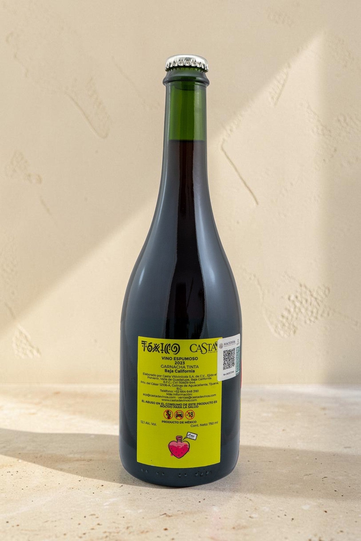 Botella de vino tinto espumoso Toxico de Wellnex con etiqueta amarilla distintiva sobre superficie de piedra