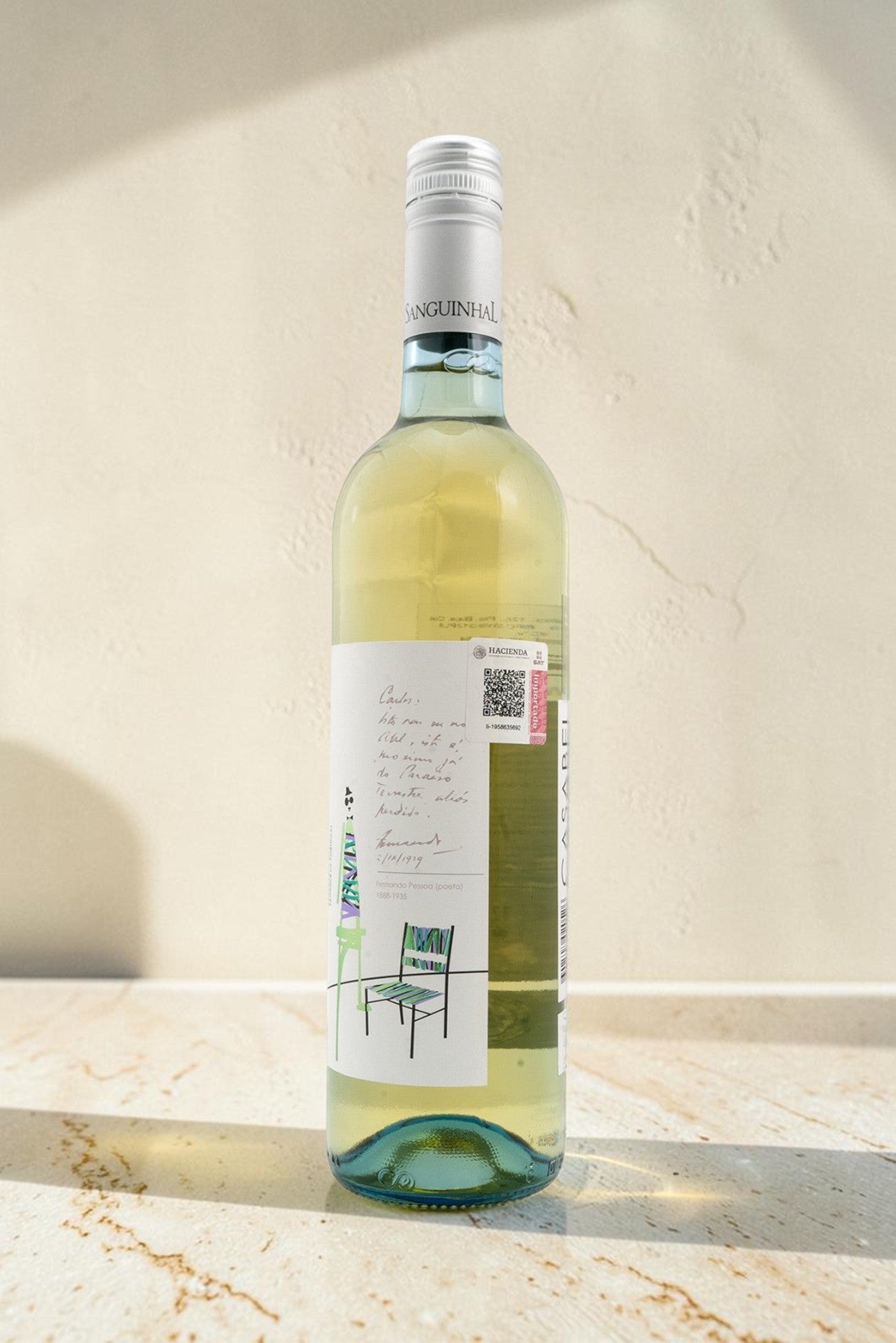 Botella de vino blanco Wellnex Casabel con etiqueta ilustrada sobre superficie de piedra clara