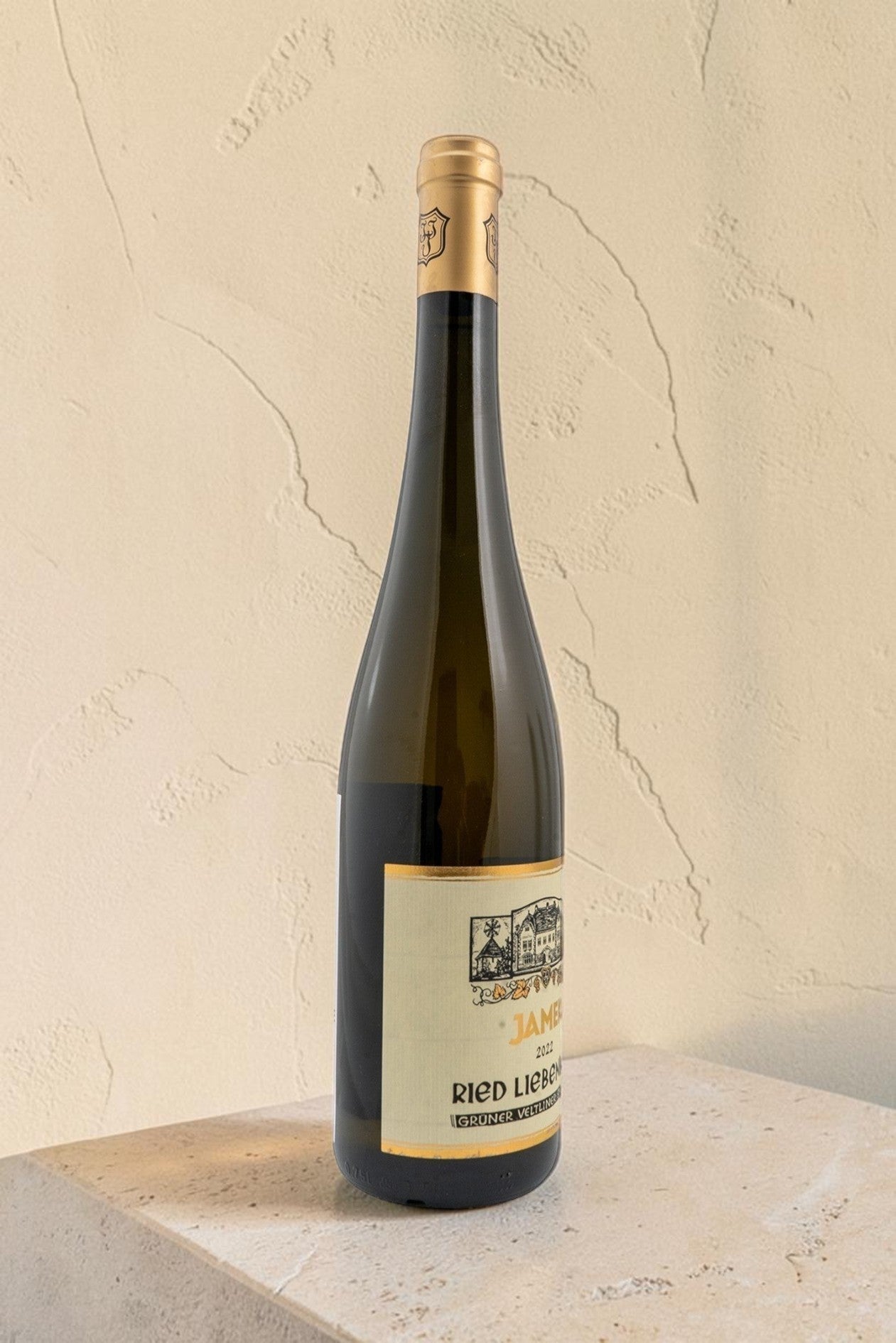 Botella de vino blanco Wellnex Weingut Jamek Ried Liebenberg Gruner Veltliner Smaragd sobre superficie clara