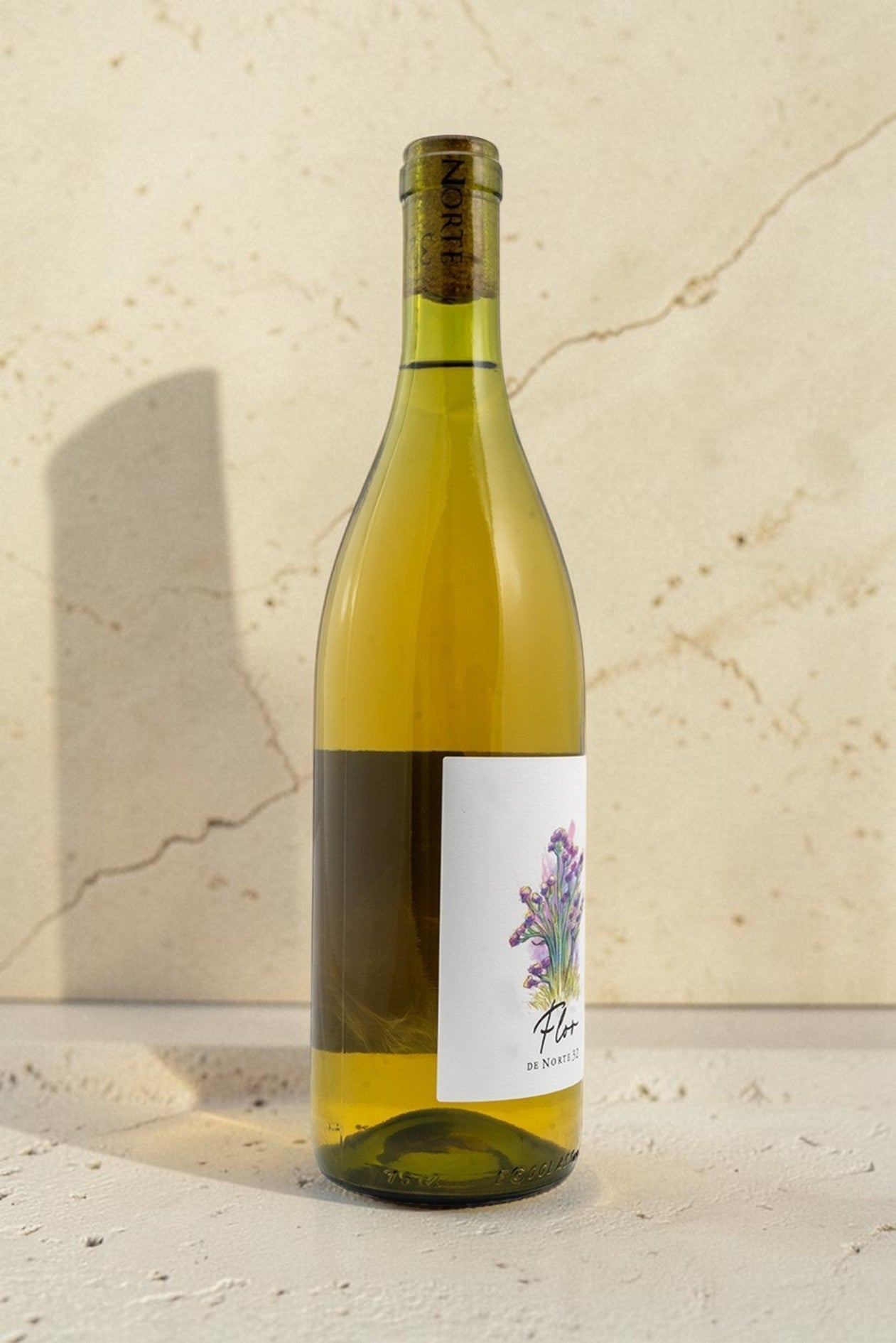 Botella de vino blanco Wellnex Norte 32 Flor de Norte 32 con etiqueta floral sobre superficie de mármol