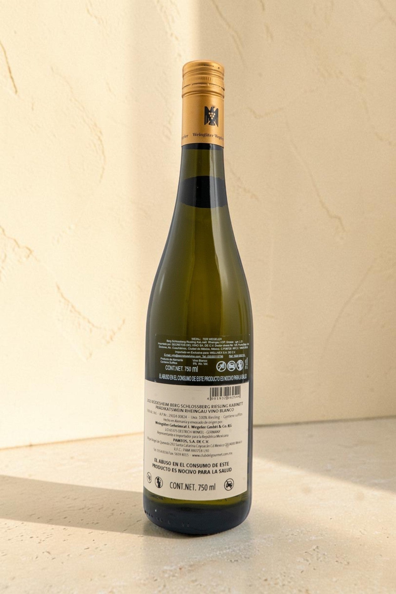 Botella de vino blanco Wellnex Weingut Wegeler Riesling Kabinett con etiqueta trasera detallada sobre fondo texturizado