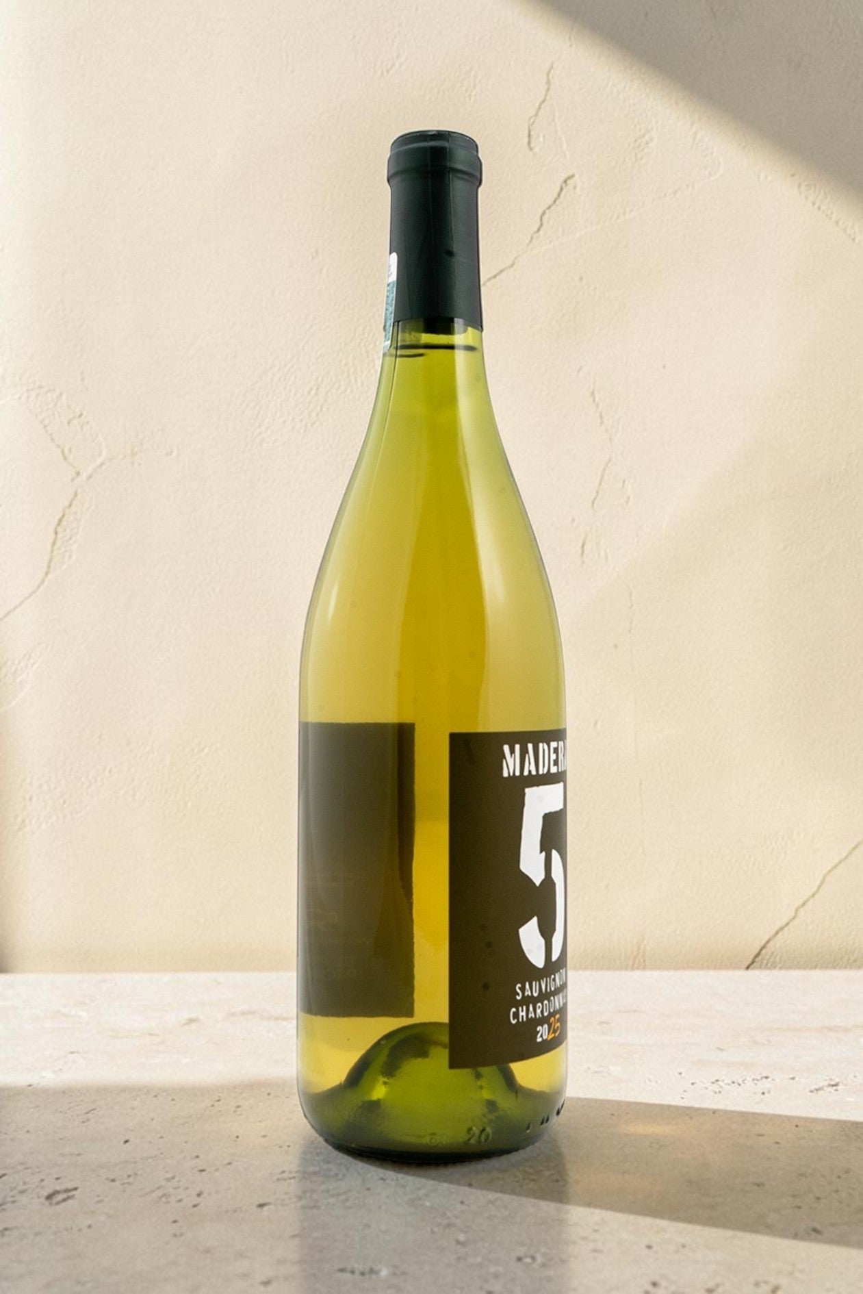 Botella de vino blanco Wellnex Sauvignon-Chardonnay de color amarillo paja brillante sobre fondo de piedra