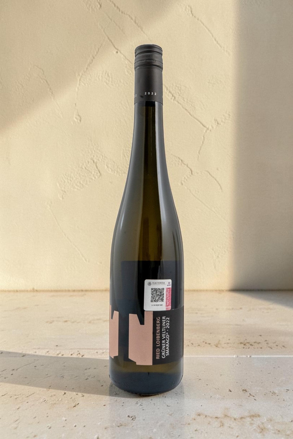 Botella de vino blanco Wellnex Weingut Tegernseerhof Gruner Veltliner Smaragd 2022 sobre superficie de piedra