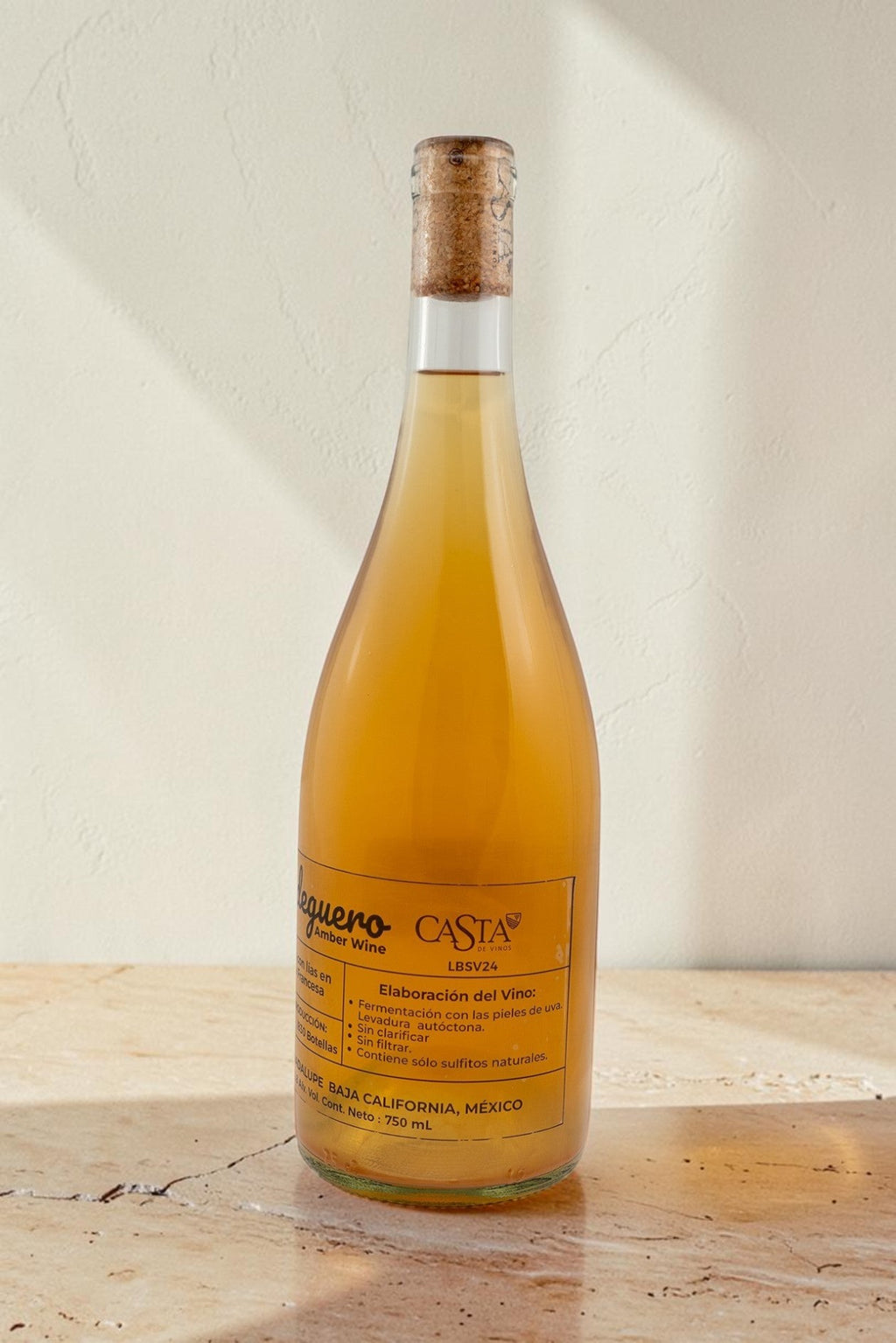 Botella de vino natural ámbar Bodeguero de Wellnex con etiqueta informativa sobre fondo neutro iluminado