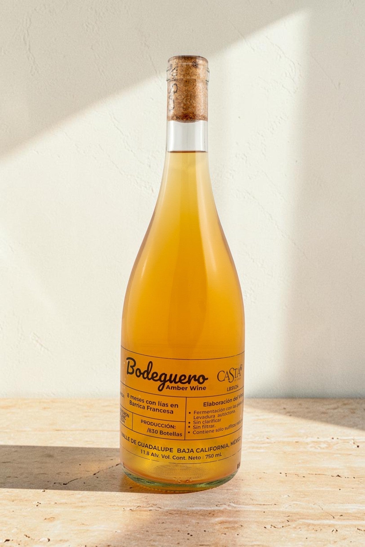 Botella de vino natural ámbar Bodeguero de Wellnex, con etiqueta detallada sobre fondo neutro iluminado.