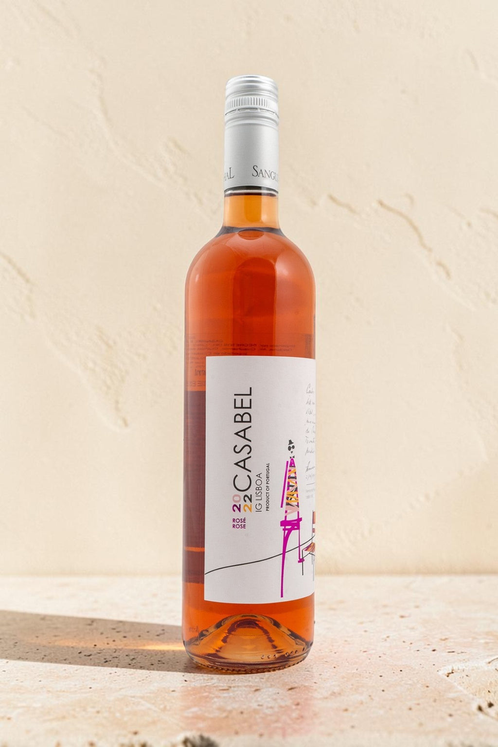 Botella de vino rosado Casabel de Wellnex con etiqueta ilustrada sobre fondo de piedra clara