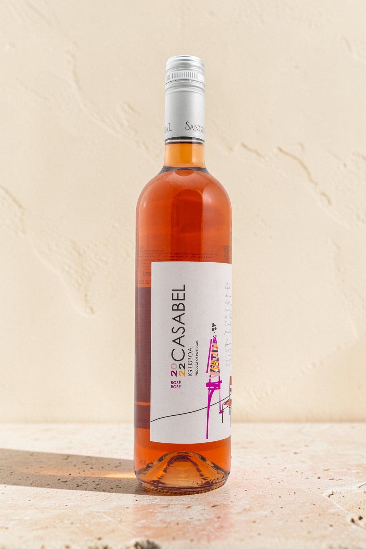 Botella de vino rosado Casabel de Wellnex con etiqueta ilustrada sobre fondo de piedra clara