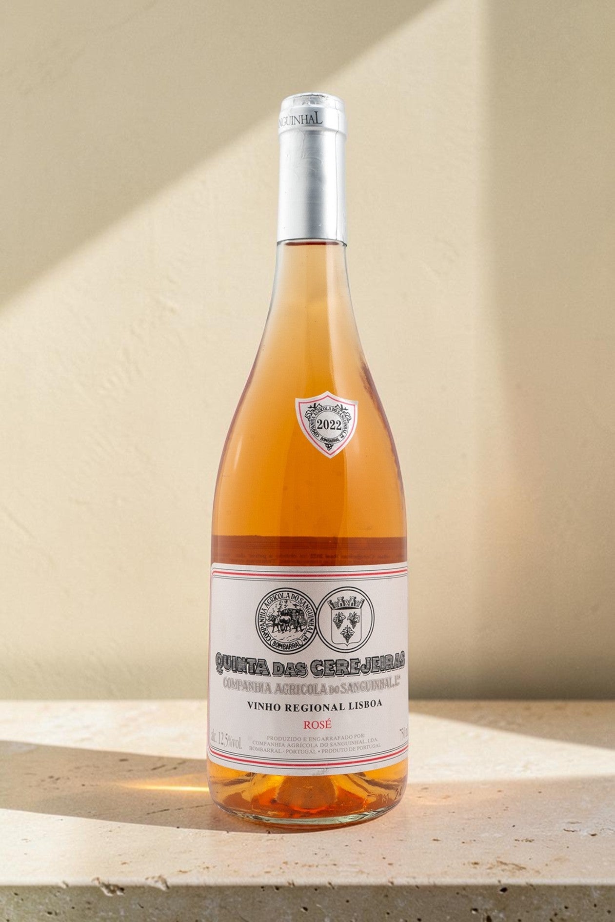 Botella de vino rosado Wellnex Gran Reserva con etiquetas clásicas sobre una superficie de piedra clara