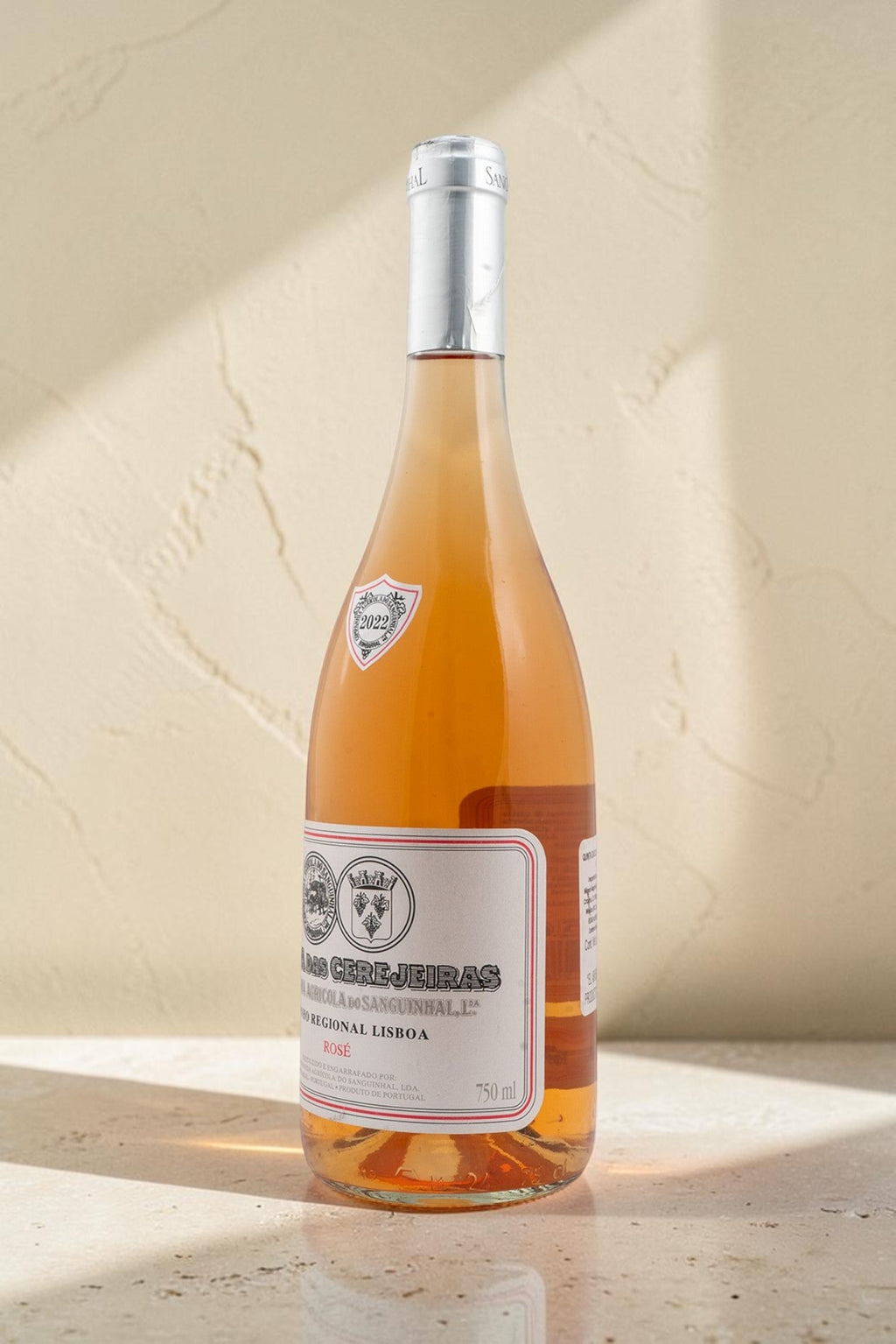 Botella de vino Gran Reserva Rosado Wellnex de color salmón pálido con etiqueta clásica sobre fondo beige