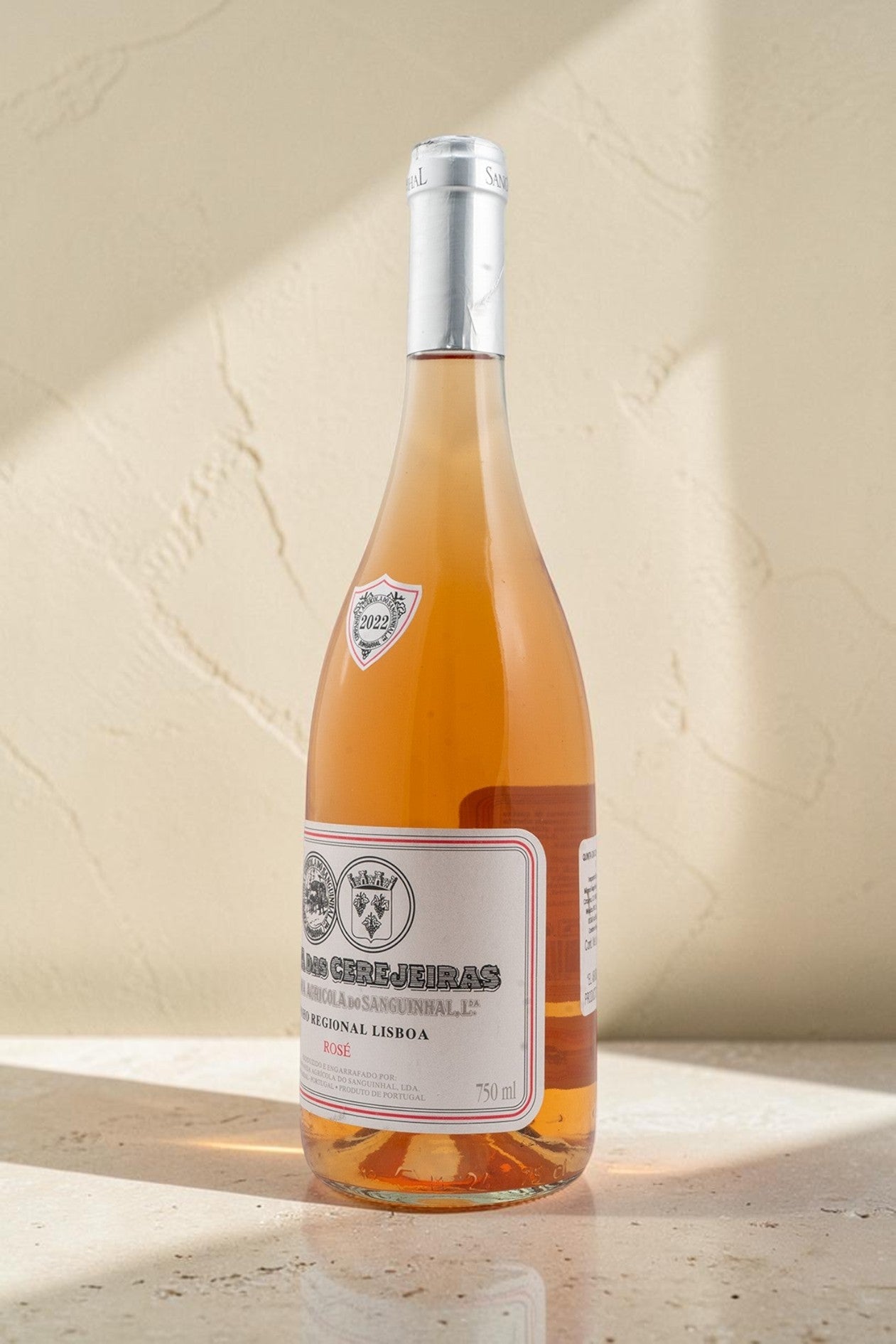 Botella de vino Gran Reserva Rosado Wellnex de color salmón pálido con etiqueta clásica sobre fondo beige