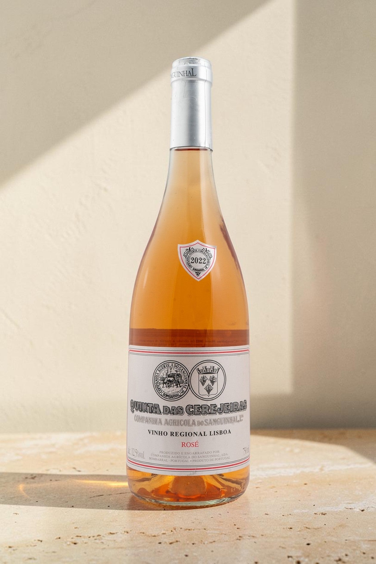 Botella de vino rosado Gran Reserva Wellnex con etiquetas de Quinta das Cerejeiras sobre superficie de piedra clara