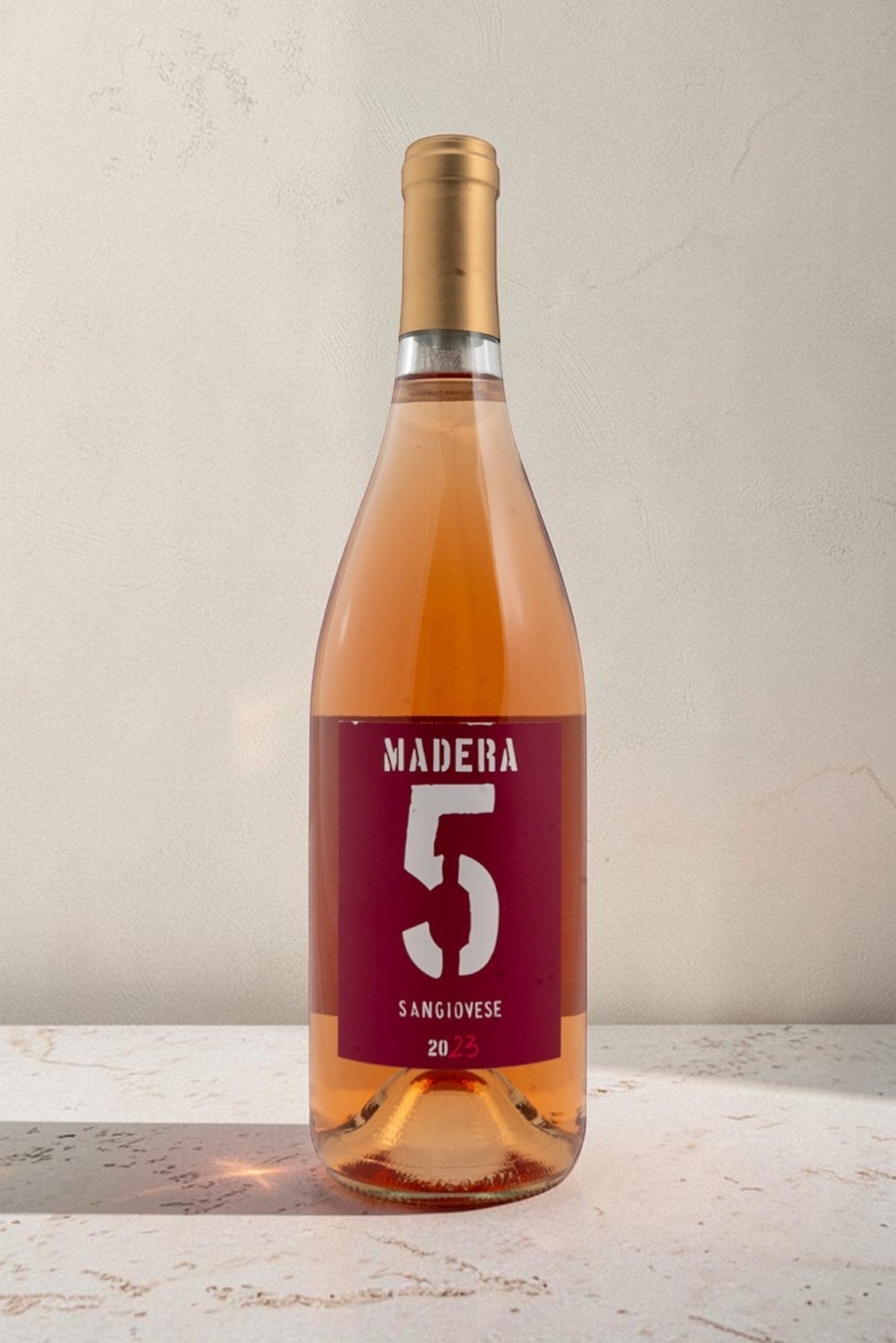 Botella de vino rosado Wellnex Madera 5 Sangiovese 2023 con tono salmón brillante y etiqueta roja