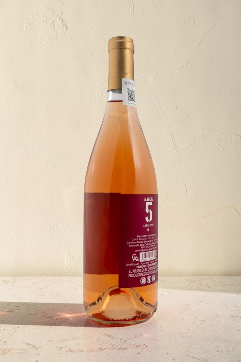 Botella de vino rosado Wellnex de color salmón brillante con etiqueta de Madera 5 sobre superficie clara