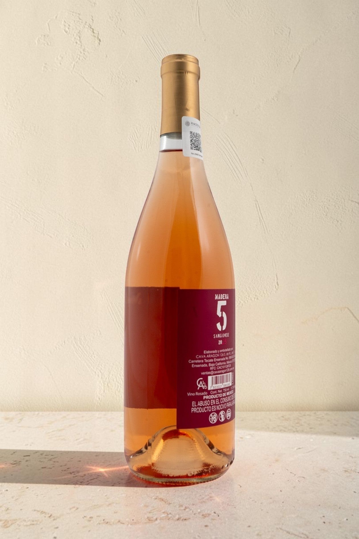 Botella de vino rosado Wellnex de color salmón brillante con etiqueta de Madera 5 sobre superficie clara
