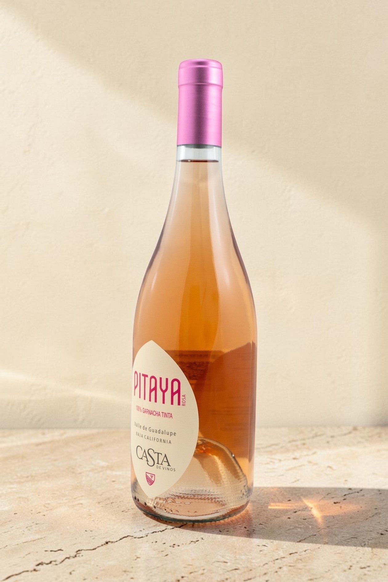 Botella de vino rosado Pitaya de Wellnex con color salmón pálido y etiqueta elegante sobre superficie de piedra