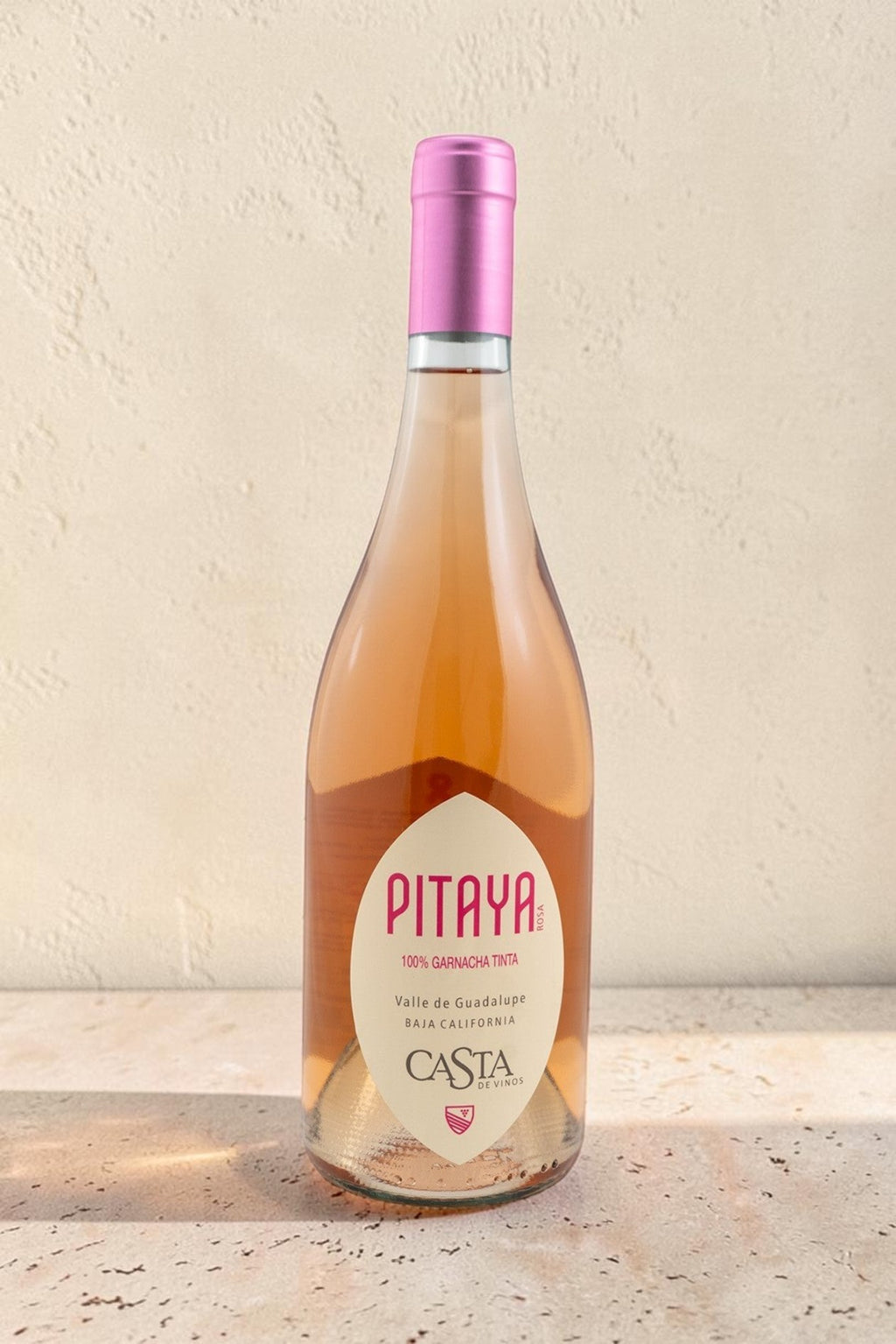 Botella de vino rosado Pitaya de Wellnex con tono salmón pálido y etiqueta elegante sobre superficie de piedra