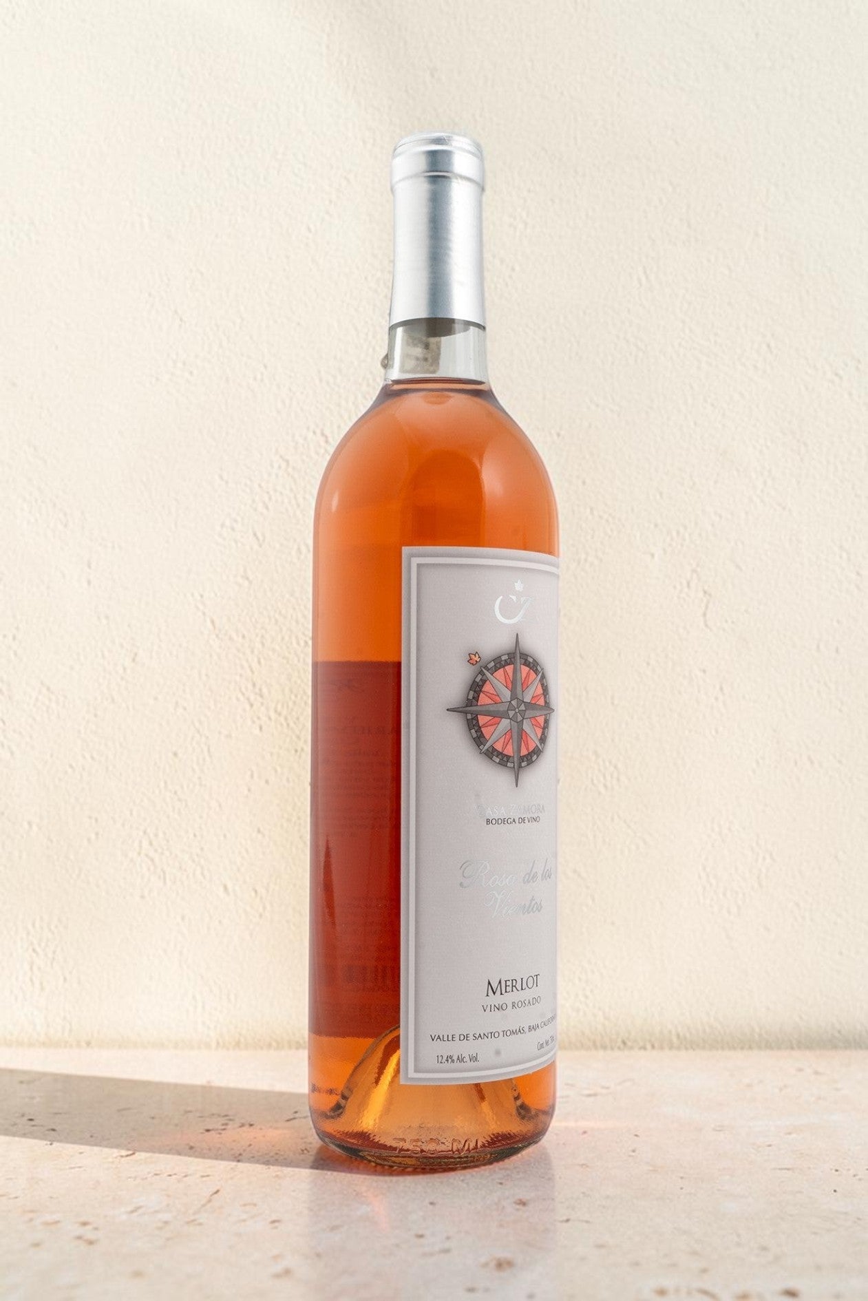 Botella de vino rosado Wellnex Rosa de Los Vientos con etiqueta de brújula sobre fondo neutro