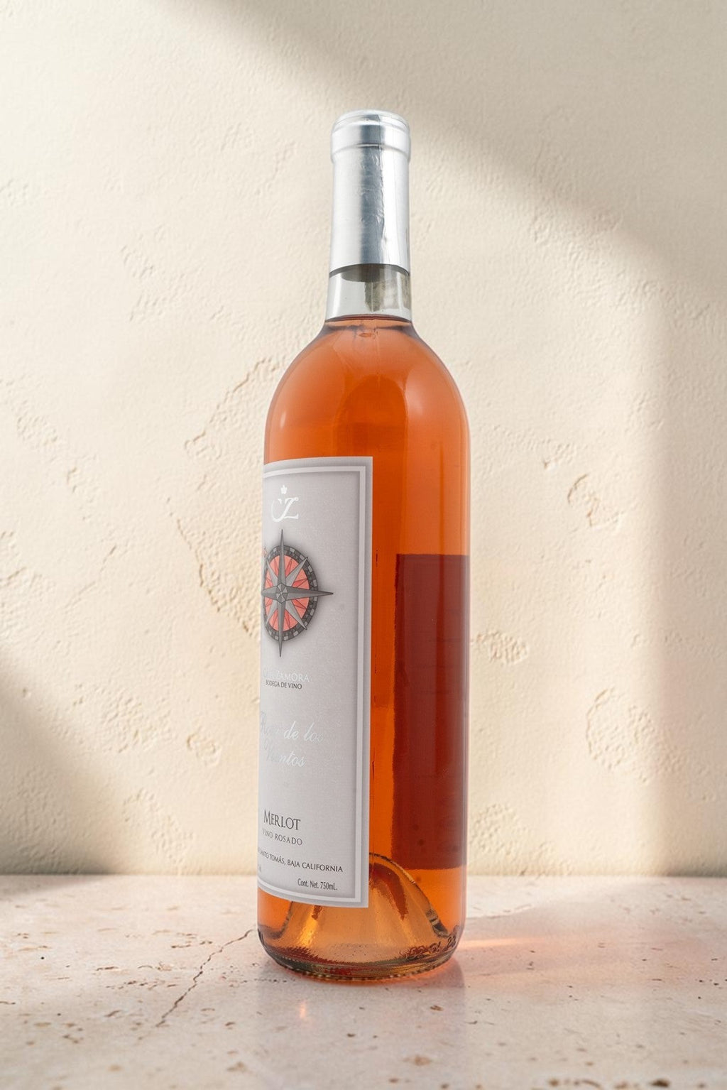 Botella de vino rosado Wellnex Rosa de Los Vientos con etiqueta de brújula sobre fondo neutro