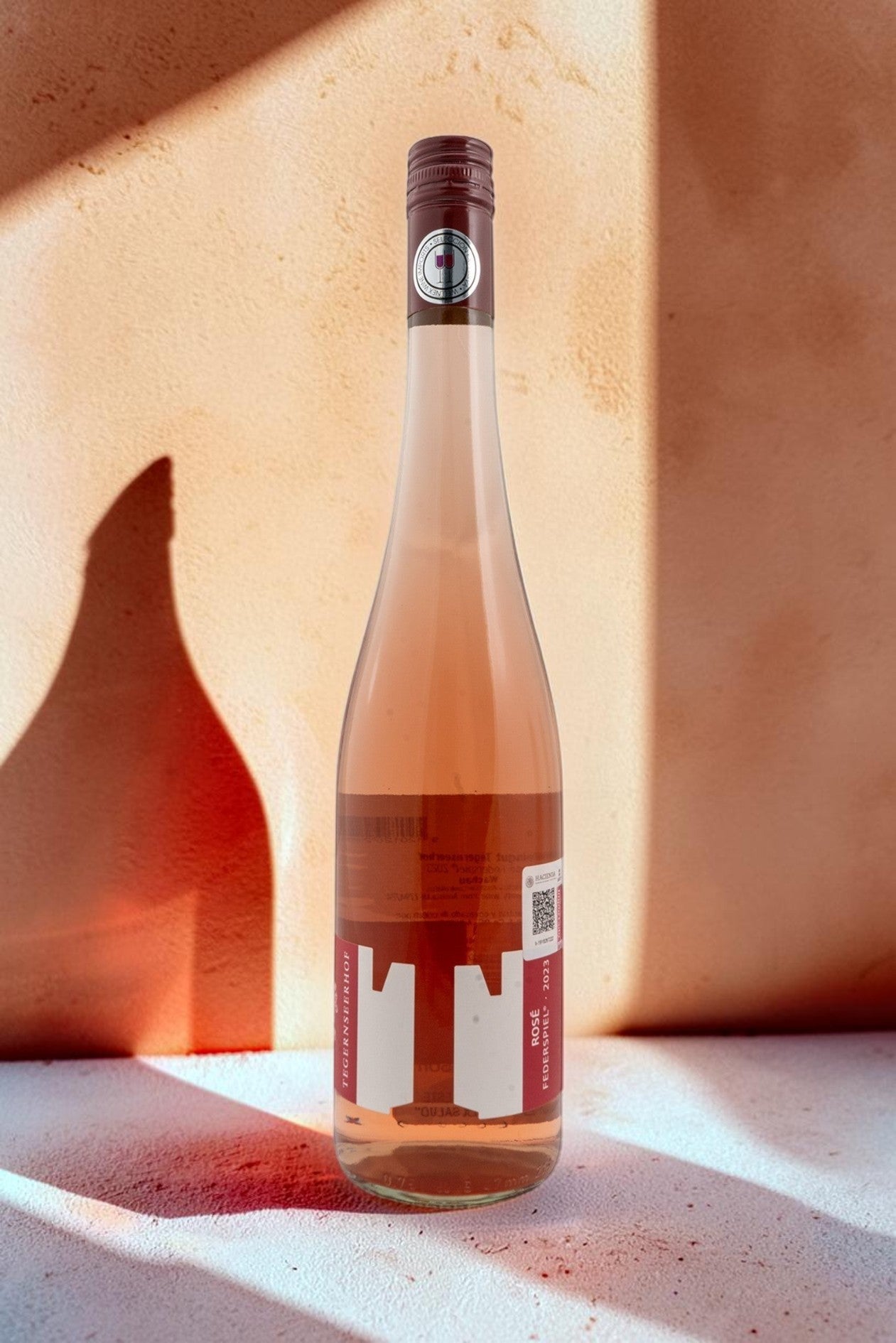 Botella de vino rosado Wellnex Weingut Tegernseerhof Federspiel con etiqueta moderna sobre fondo neutro