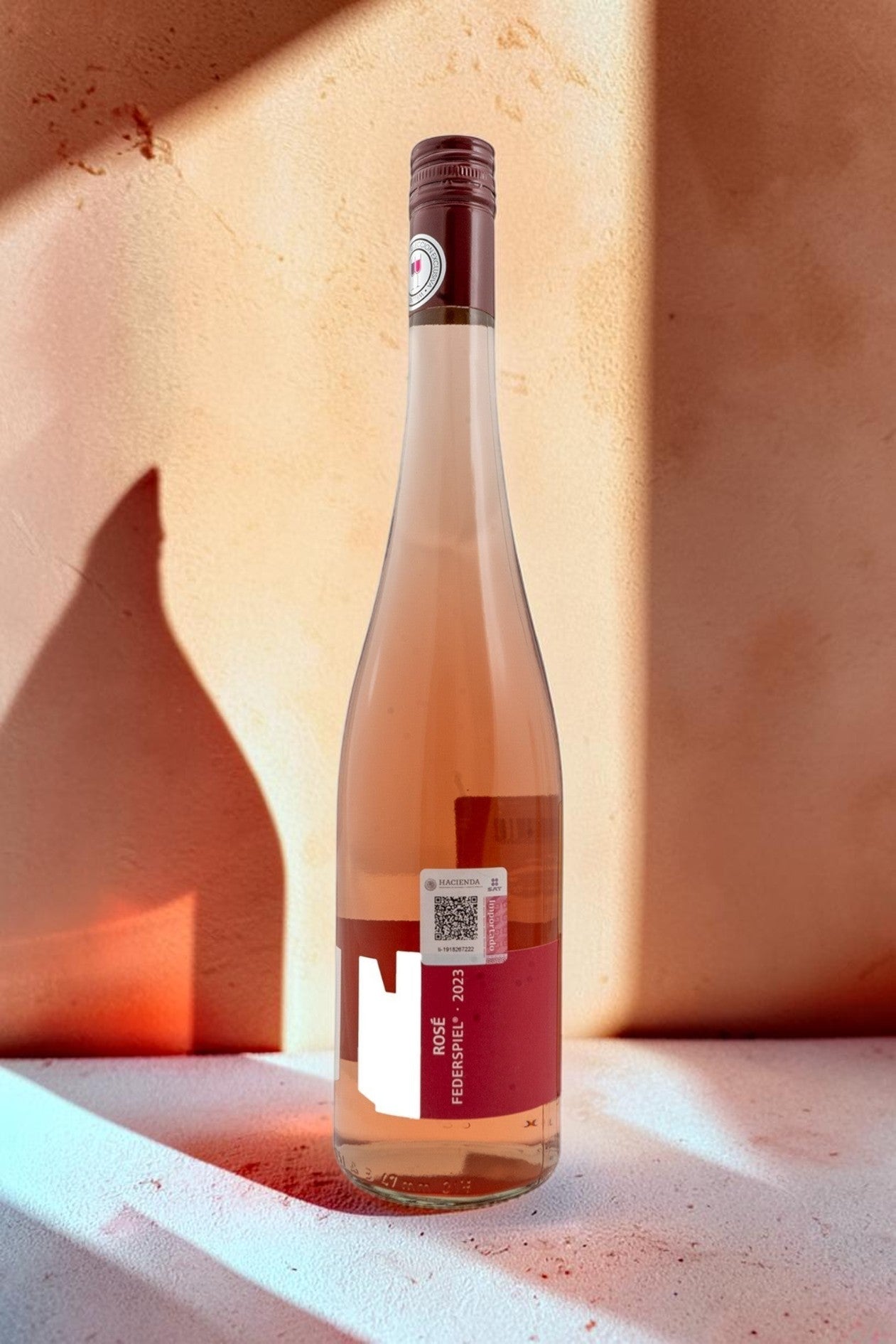 Botella de vino rosado Wellnex Weingut Tegernseerhof Federspiel con etiquetas rojas sobre fondo neutro