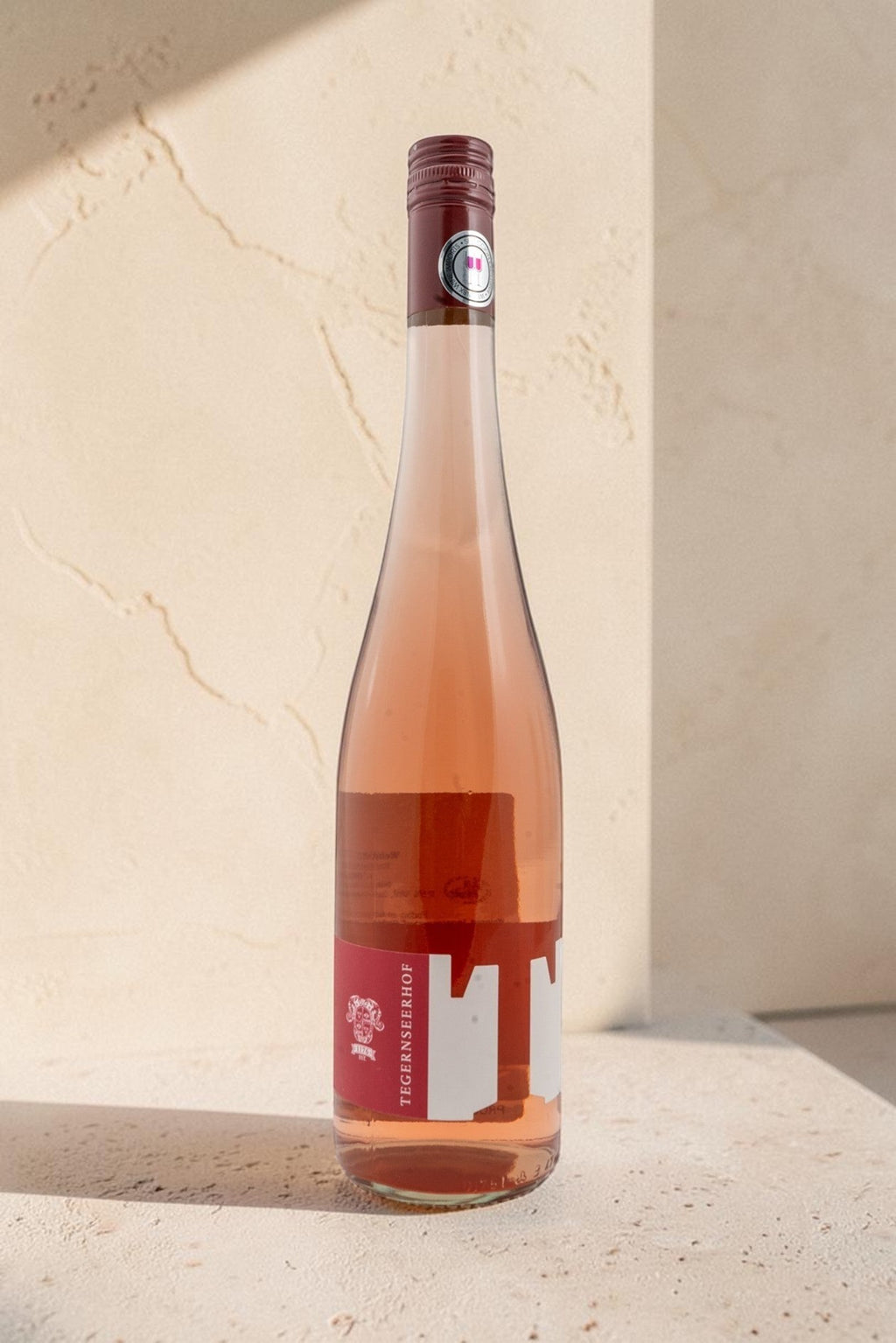 Botella de vino rosado Wellnex Weingut Tegernseerhof VR Federspiel con etiqueta roja sobre superficie clara