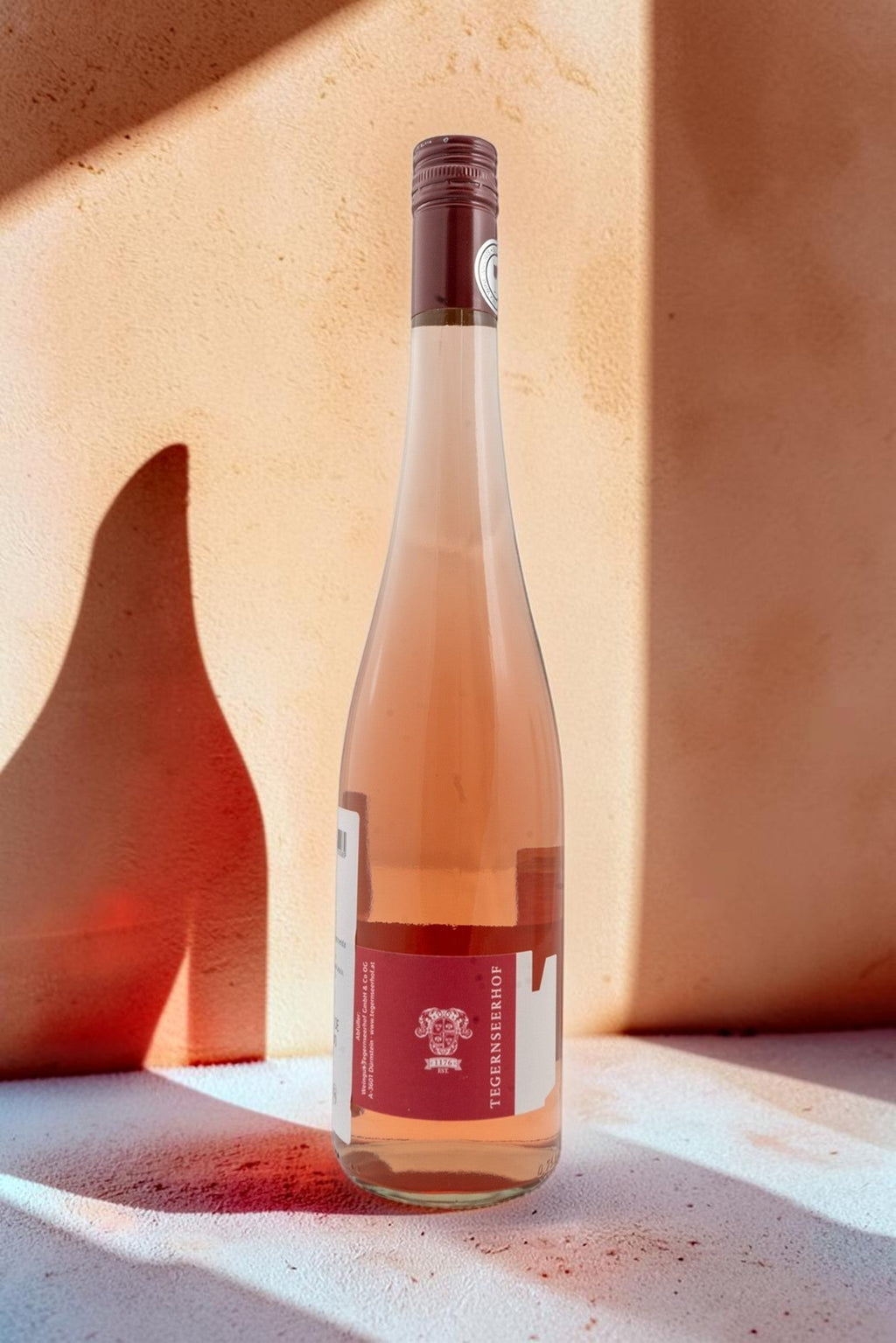 Botella de vino rosado Wellnex Weingut Tegernseerhof VR Federspiel con tonos salmón y etiqueta roja distintiva