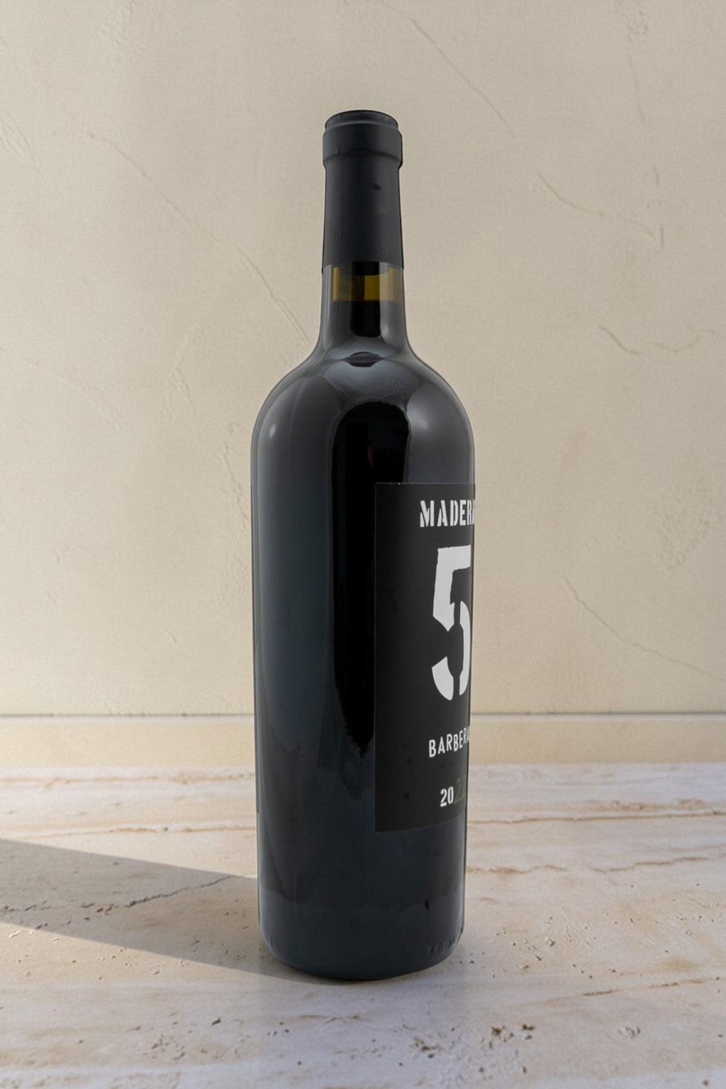 Botella de vino tinto Wellnex Barbera de color rojo rubí con etiqueta negra moderna sobre fondo neutro