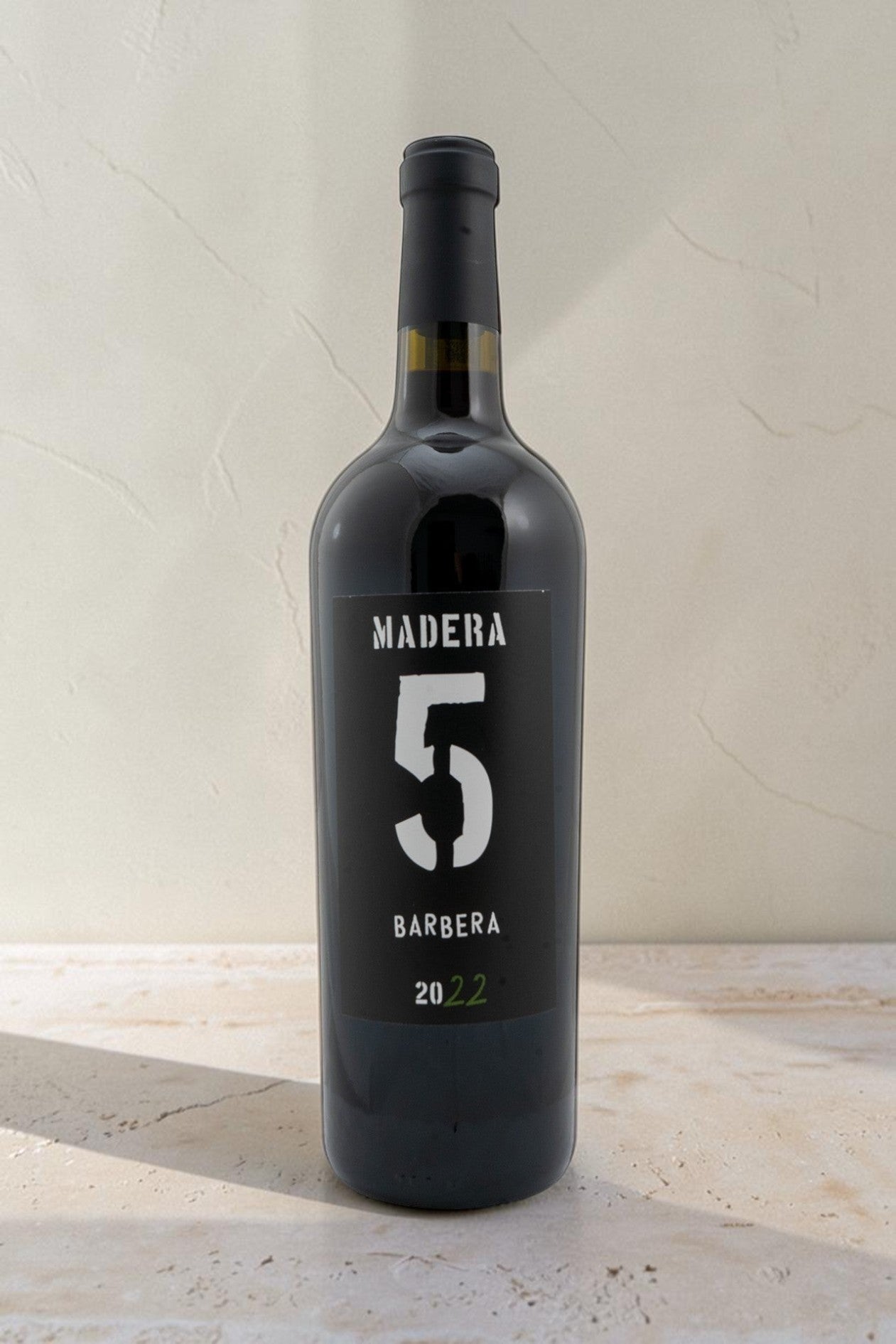 Botella de vino tinto Wellnex Barbera 2022 con etiqueta negra, diseño minimalista y color rojo rubí intenso.