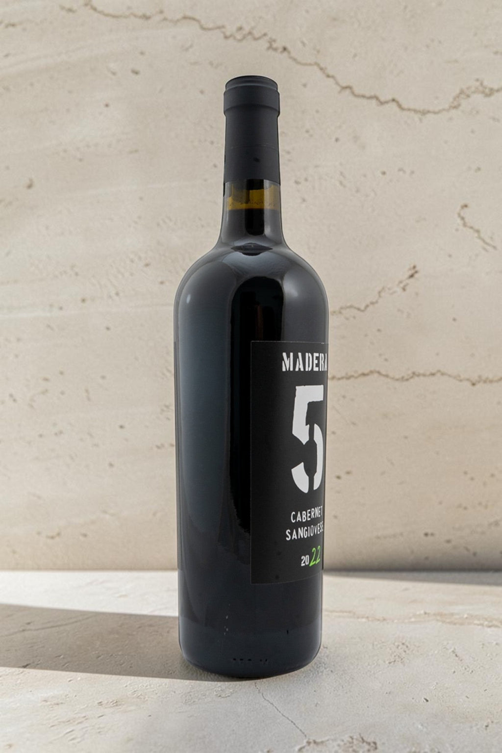 Botella de vino tinto Wellnex Cabernet Sangiovese 2022 con etiqueta negra y número 5 sobre fondo neutro