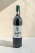 Botella de vino tinto Wellnex Cardon con etiqueta minimalista sobre fondo texturizado color crema