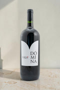 Botella de vino tinto Domina de Wellnex con etiqueta blanca minimalista sobre fondo neutro