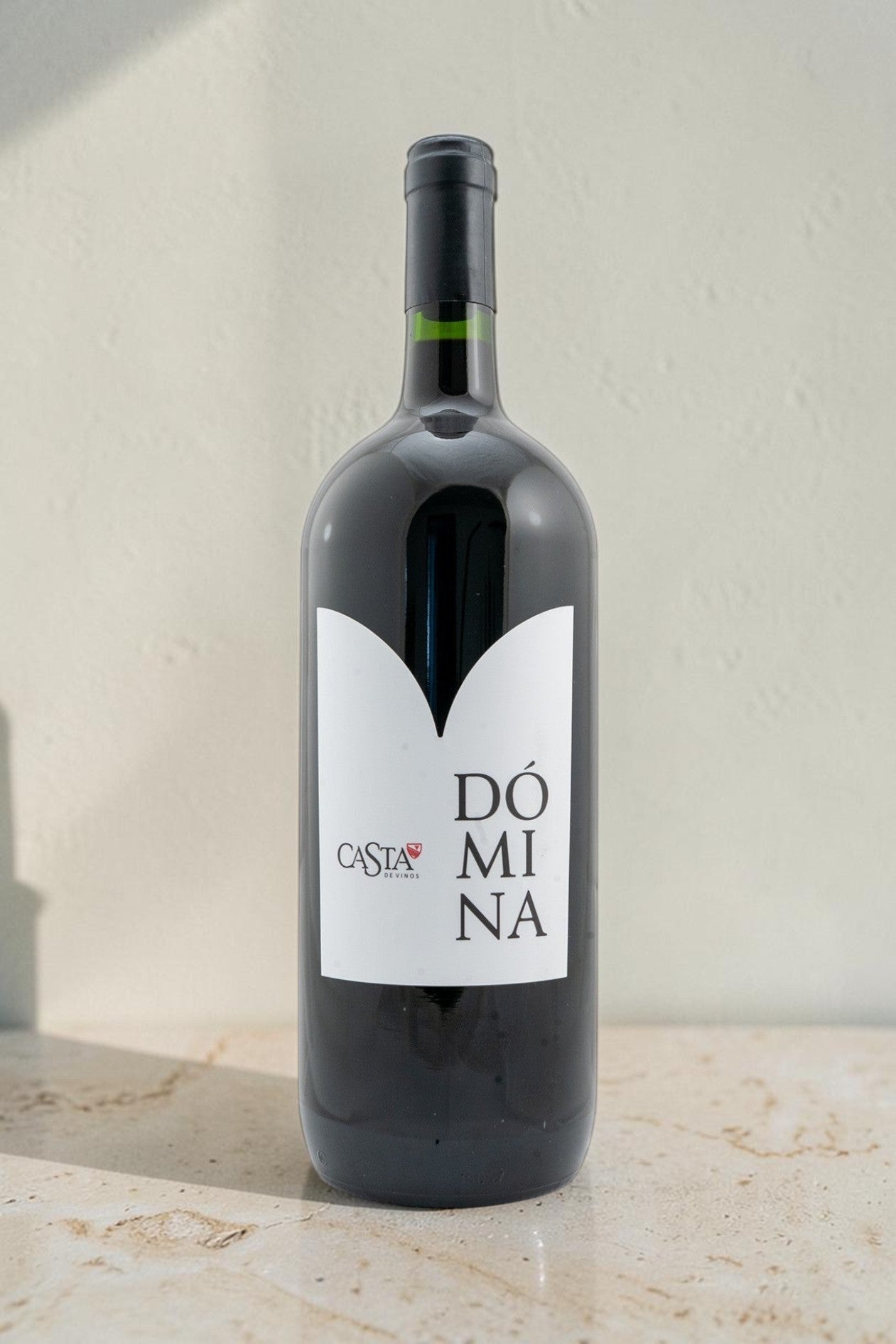 Botella de vino tinto Domina de Wellnex con etiqueta blanca minimalista sobre fondo neutro