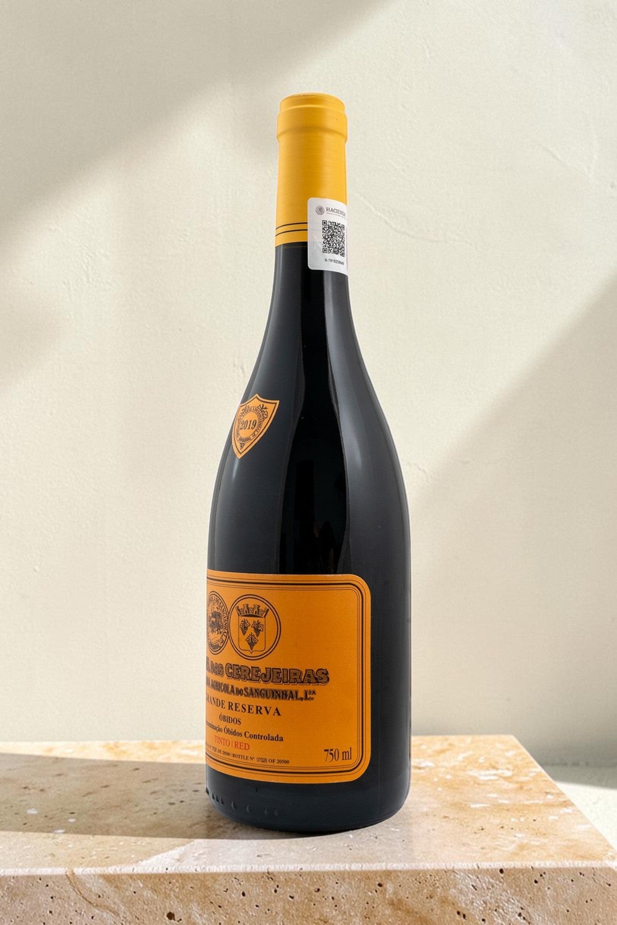 Botella de vino tinto Wellnex Gran Reserva con etiqueta amarilla, notas de cereza y vainilla sobre base de piedra.