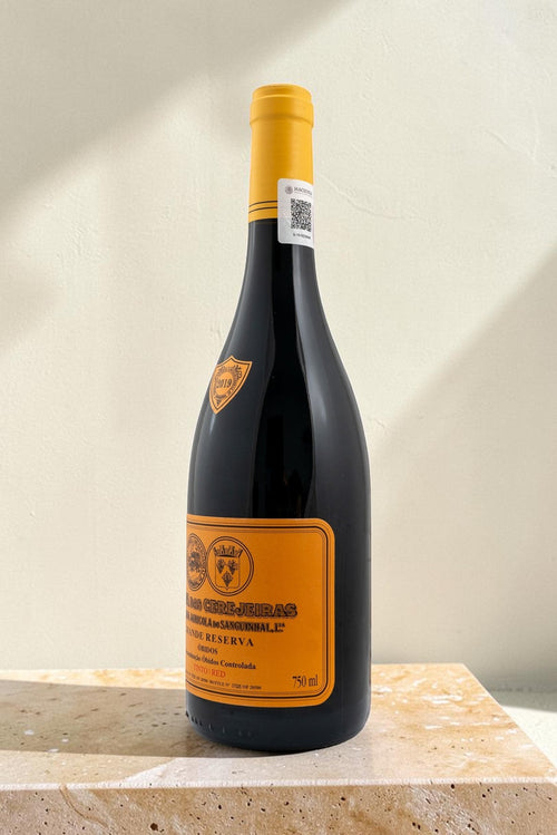 Botella de vino tinto Wellnex Gran Reserva con etiqueta amarilla, notas de cereza y vainilla sobre base de piedra.