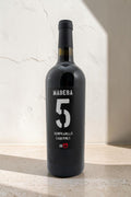 Botella de vino tinto Wellnex Madera 5 Tempranillo Cabernet 2019 con etiqueta negra elegante sobre fondo neutro