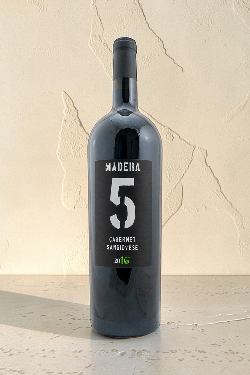 Botella de vino tinto Wellnex Madera 5 Cabernet Sangiovese 2016 con etiqueta negra sobre fondo neutro