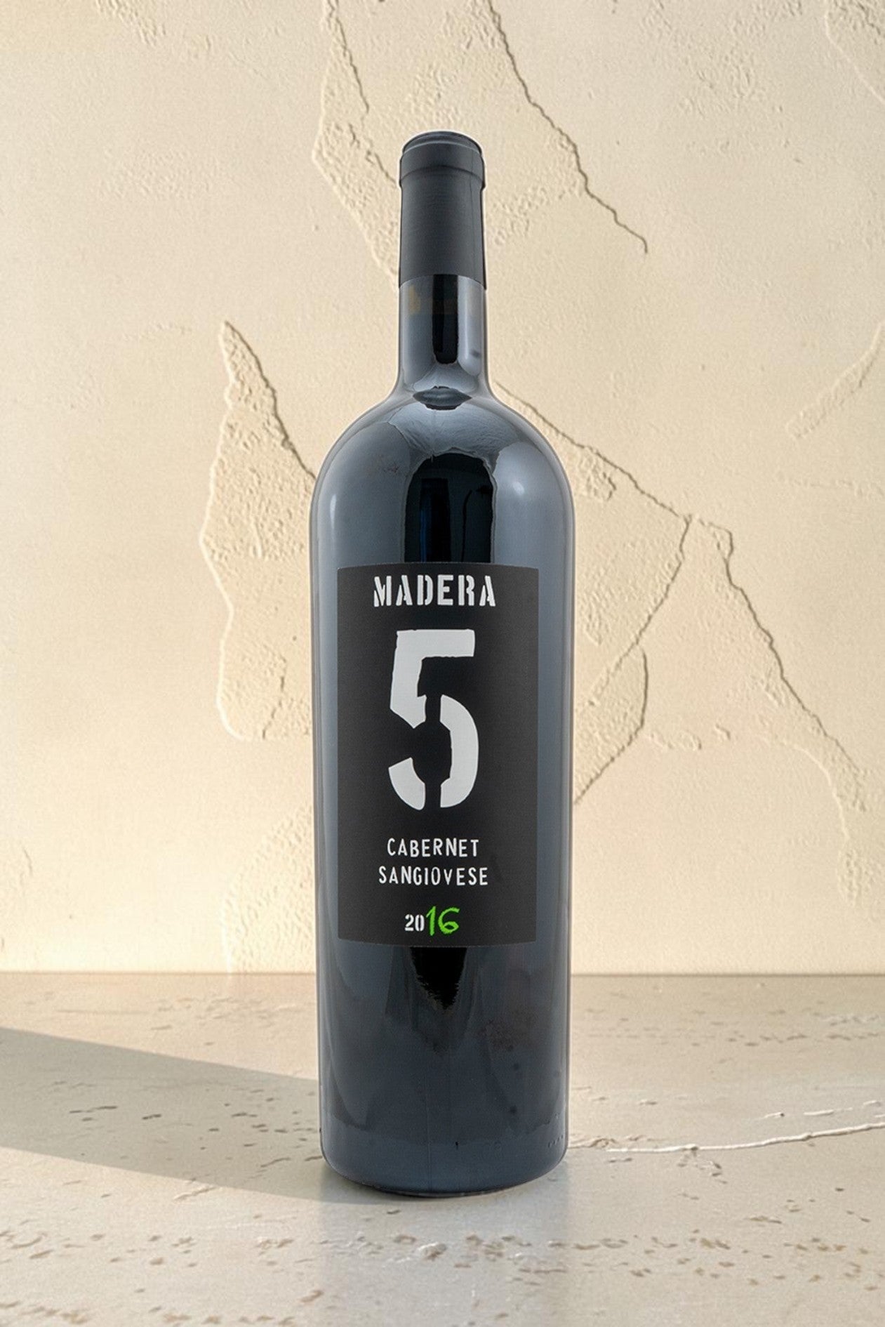 Botella de vino tinto Wellnex Madera 5 Cabernet Sangiovese 2016 con etiqueta negra sobre fondo neutro
