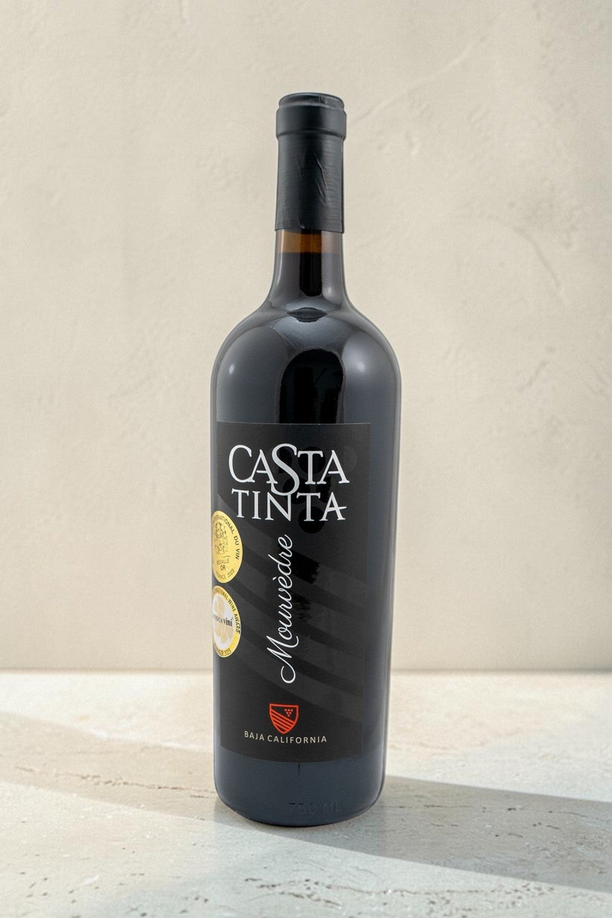 Botella de vino tinto Mourvedre Casta Tinta de Wellnex con etiqueta negra y medallas de calidad sobre fondo neutro