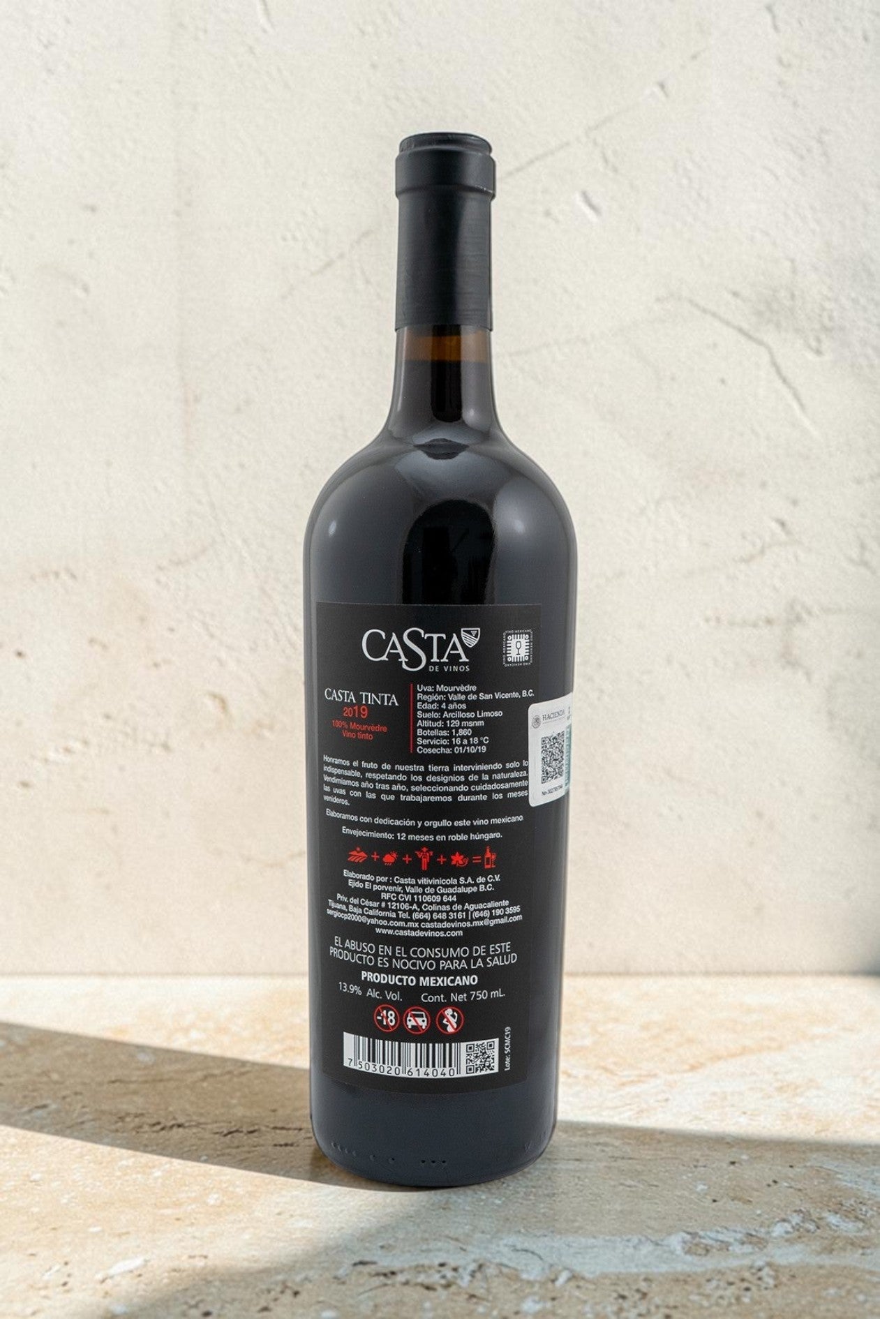 Botella de vino tinto Mourvedre Wellnex con etiqueta informativa detallada sobre fondo de piedra texturizada